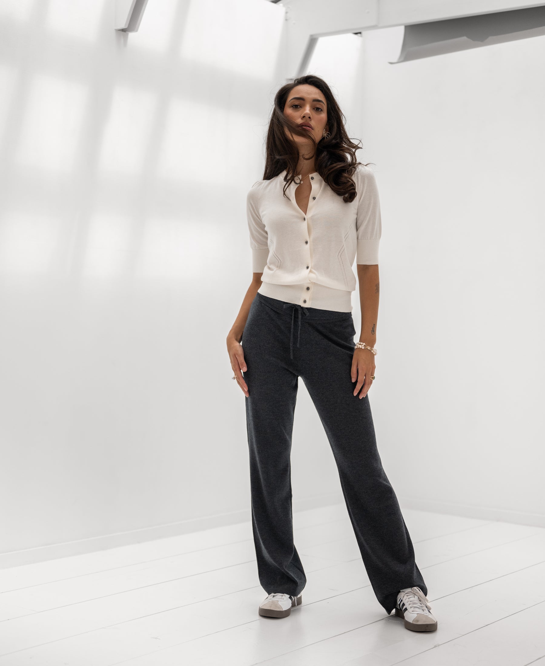 Woman wearing the Adeline vest in ivory white and gunmetal by PLEIN PUBLIQUE in a bright, minimalist room.