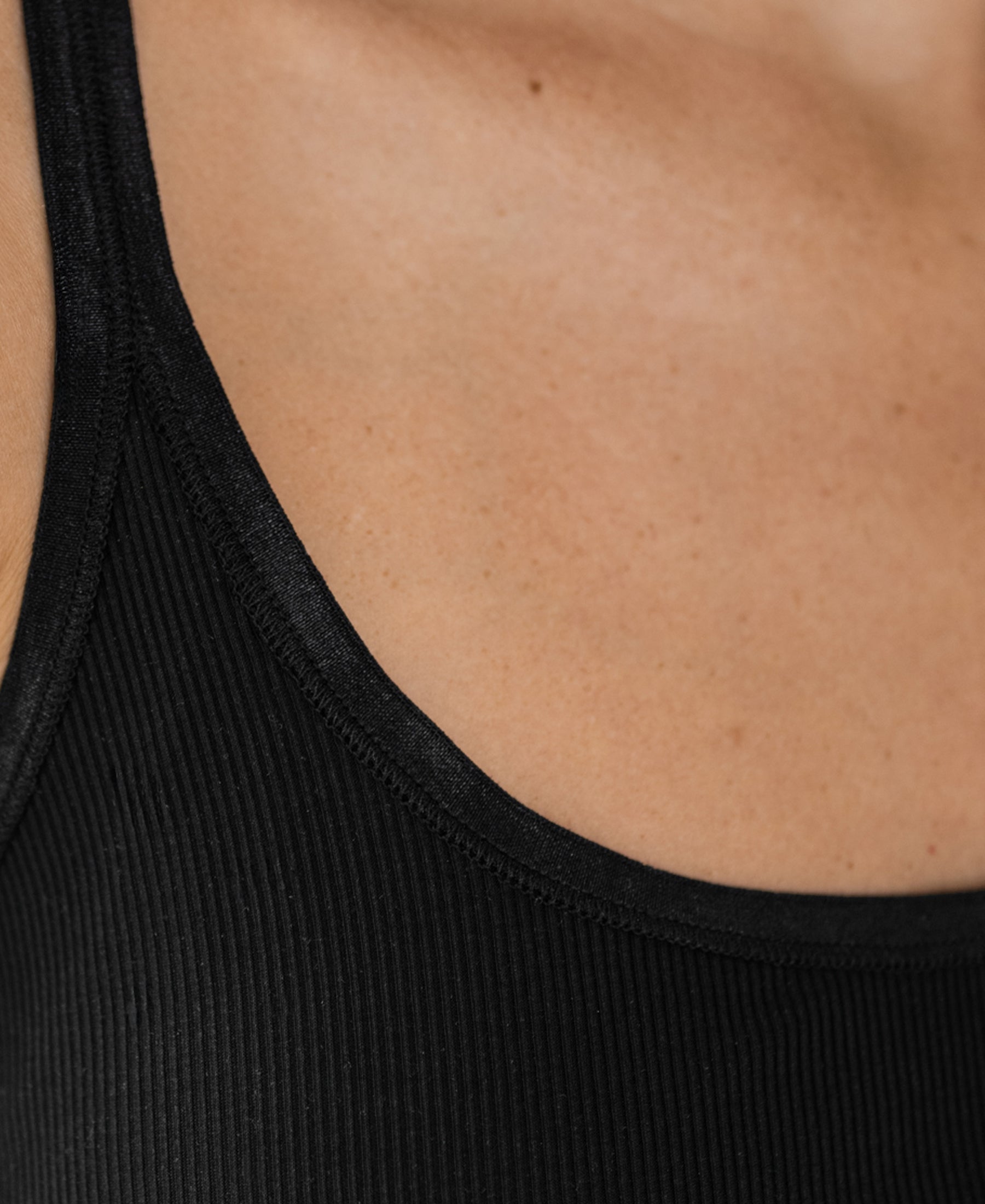 Close-up of a shoulder and upper chest wearing the Luxe Cami top LE BASTILLE Black by PLEIN PUBLIQUE.