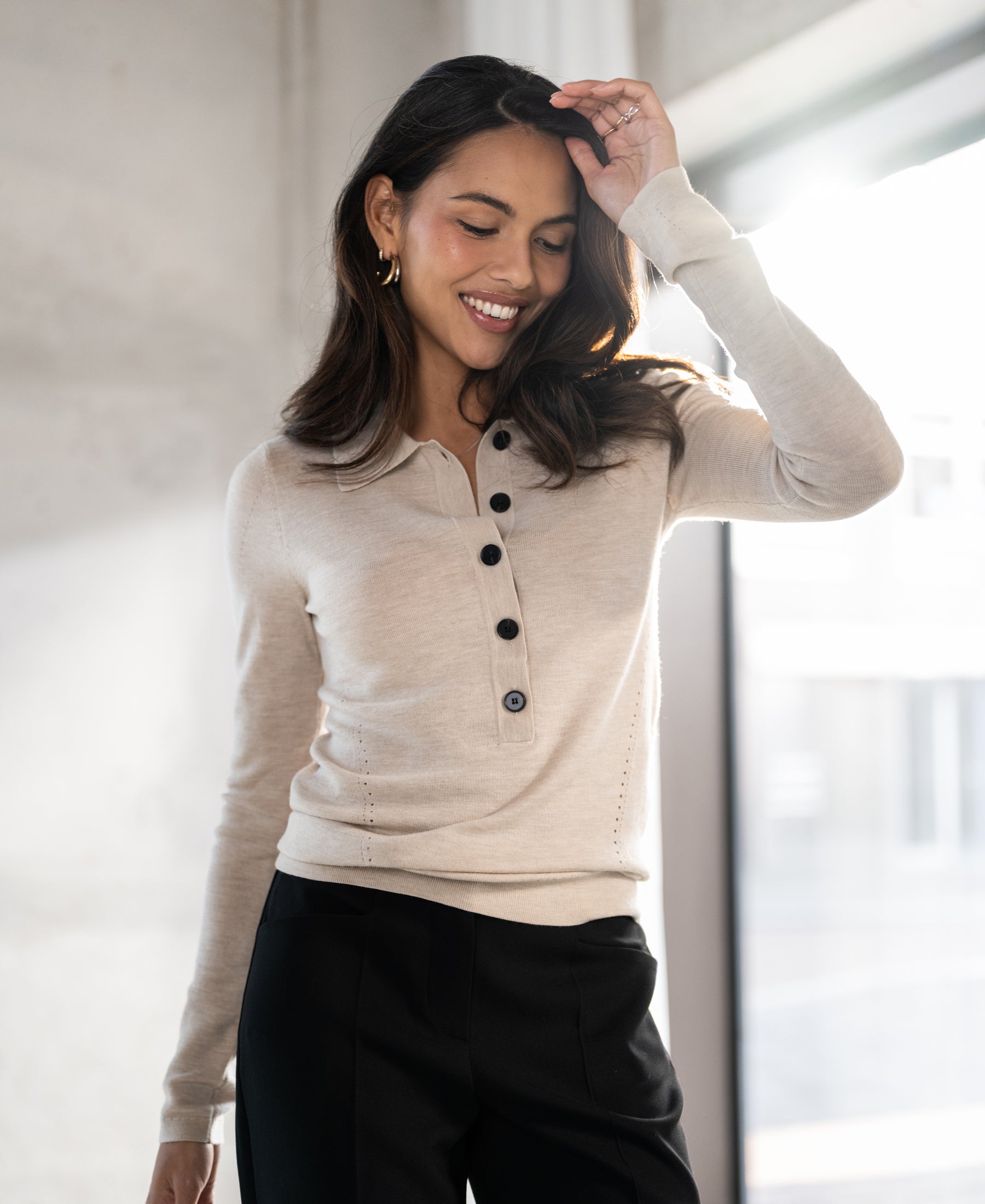 Beige merino wool polo shirt shown in bright indoor light.