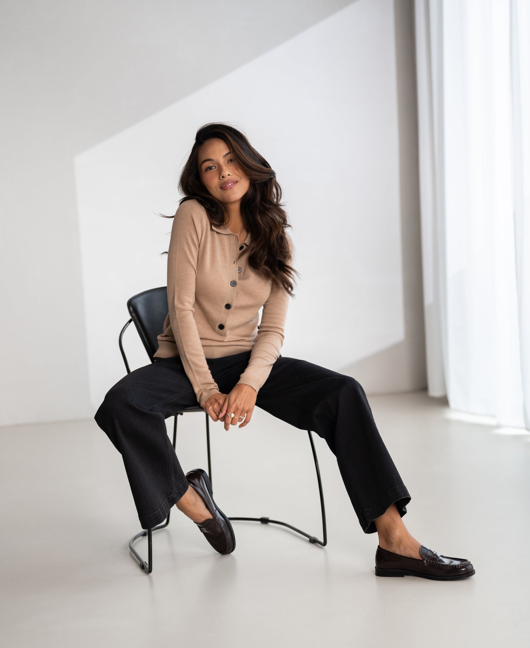 Soft camel merino wool polo shirt by PLEIN PUBLIQUE, shown on a model seated in a neutral room.