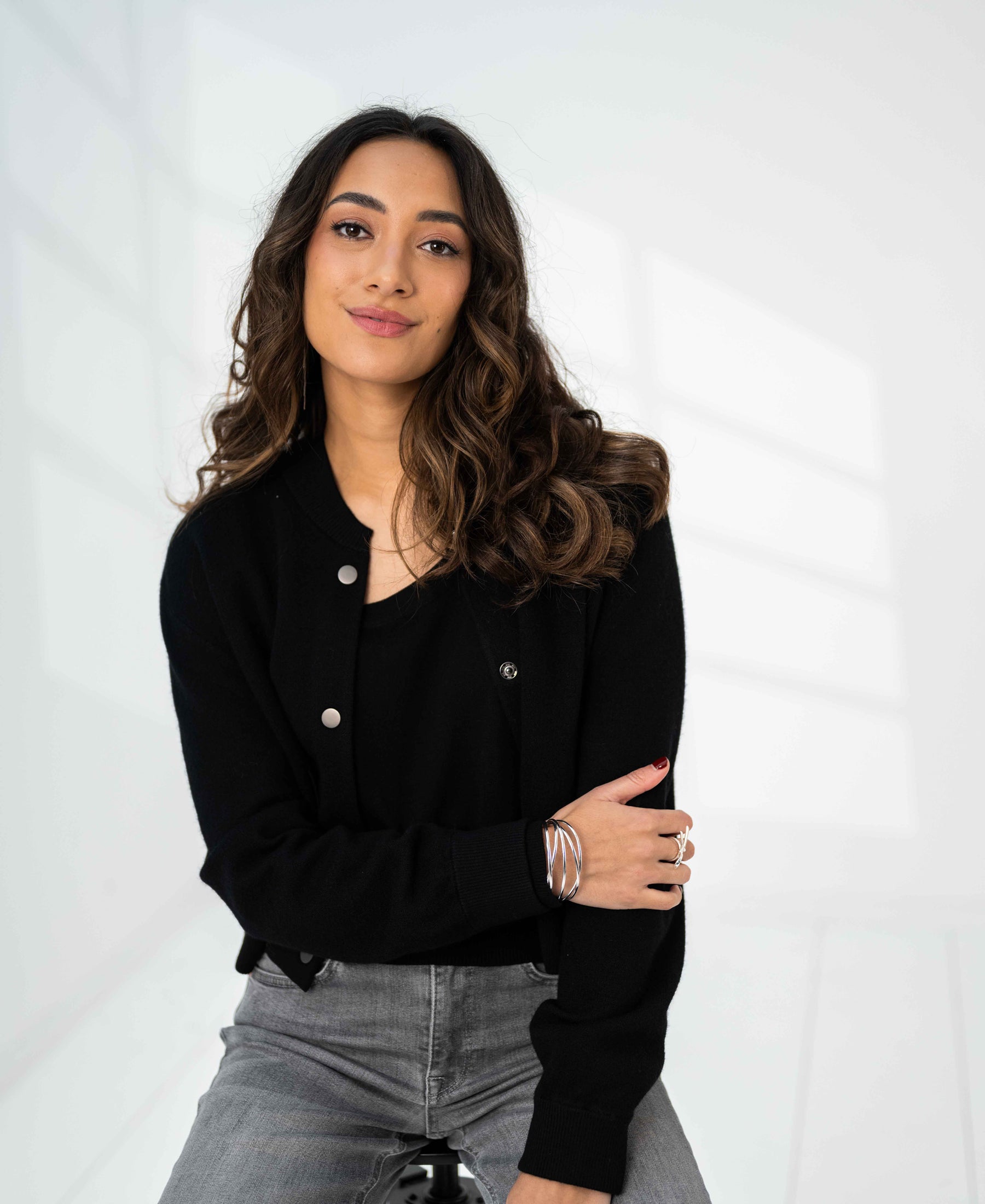Black bomber jacket LA BOMBA by PLEIN PUBLIQUE, shown worn by a model seated on a stool.