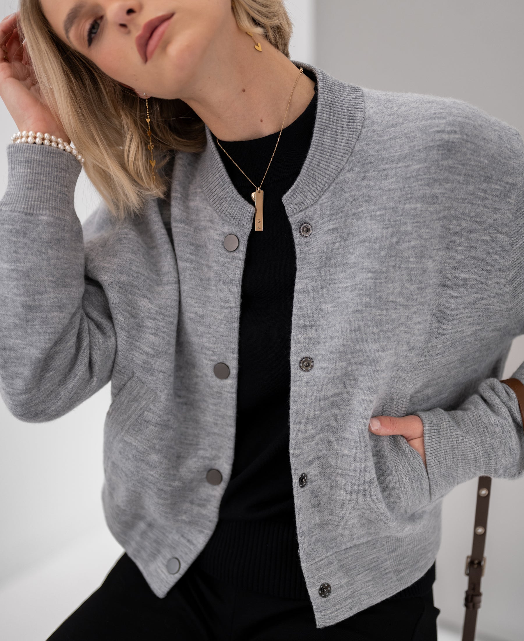 Woman poses in gray melange bomber jacket, hand in pocket.