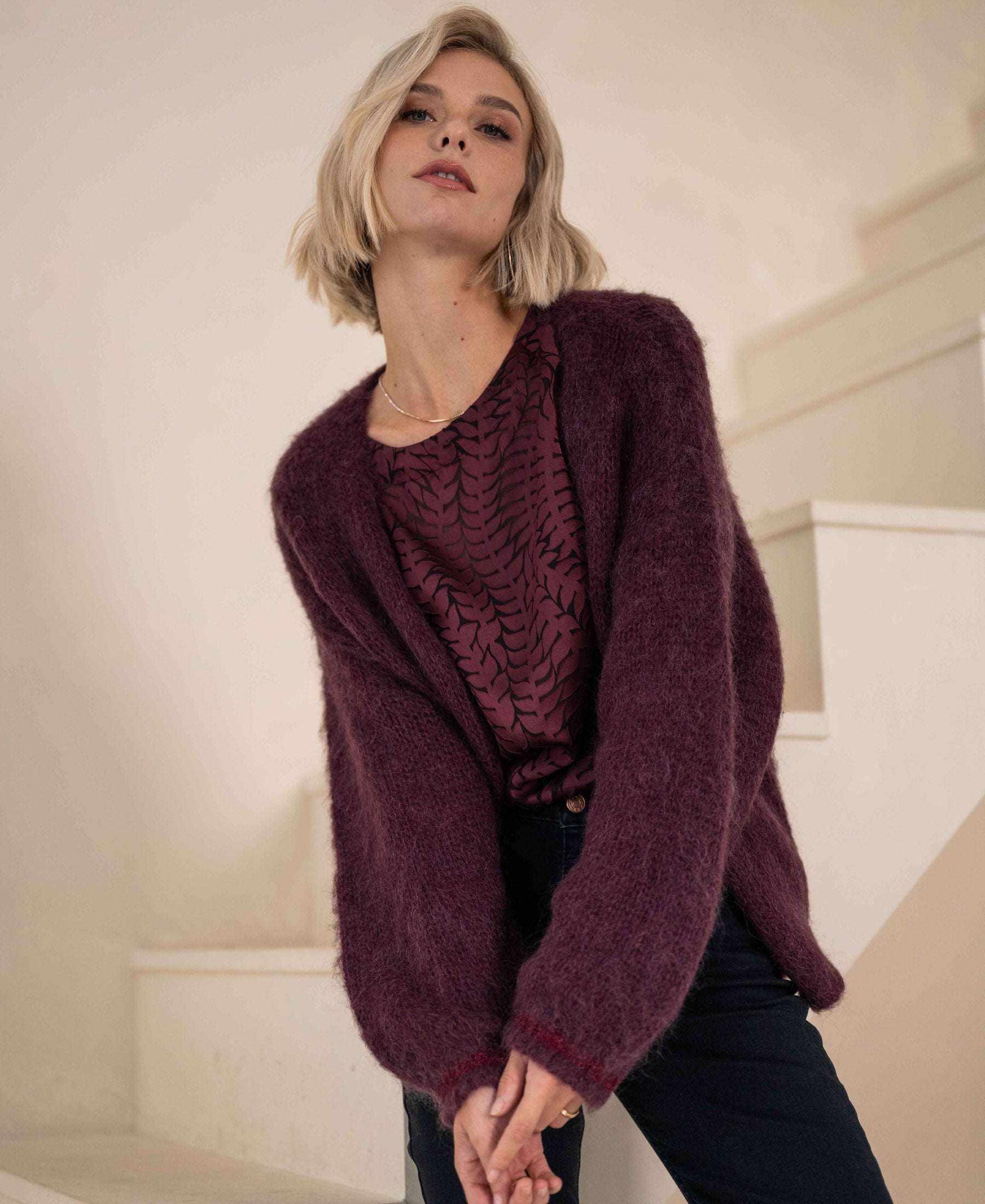 Fluffy vest in Bordeaux by PLEIN PUBLIQUE, shown indoors near a staircase.