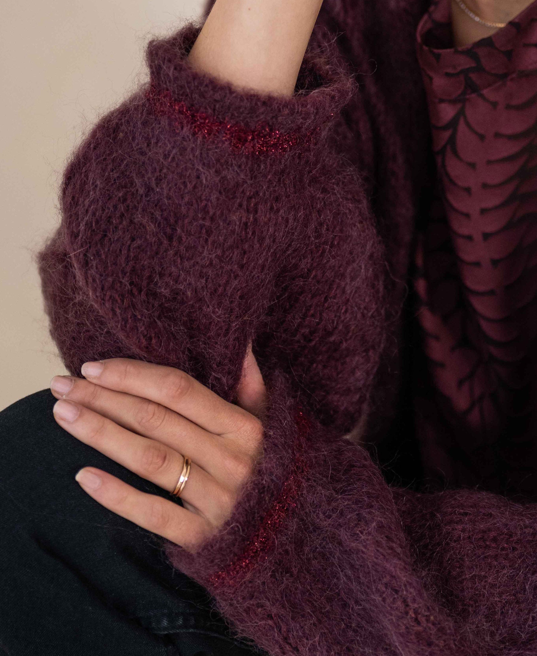 Bordeaux fluffy vest in soft material, shown on a model with one hand resting on their arm.