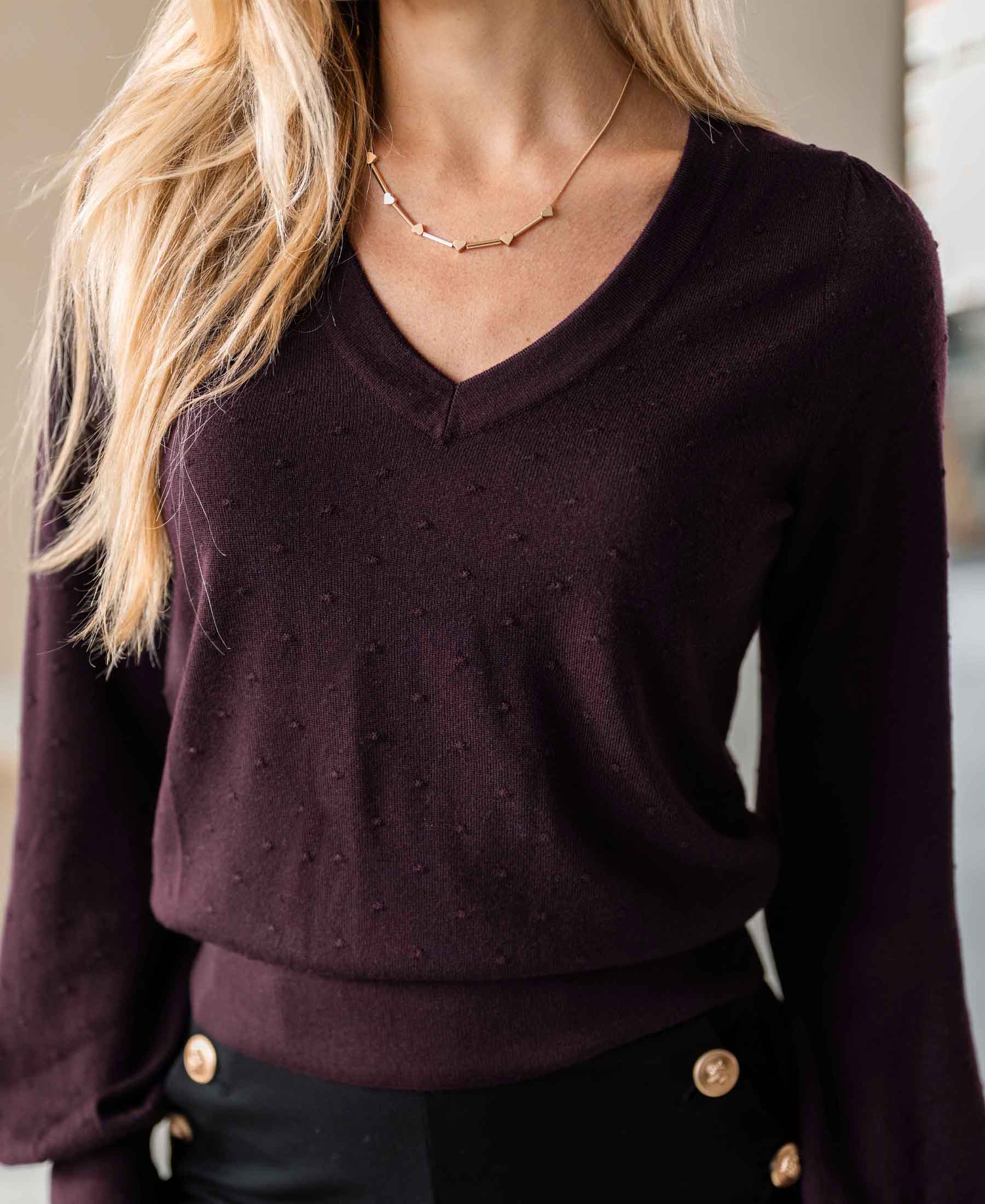 Woman wearing PLEIN PUBLIQUE Merino wool V-neck sweater in Bordeaux, shown from shoulders to waist.