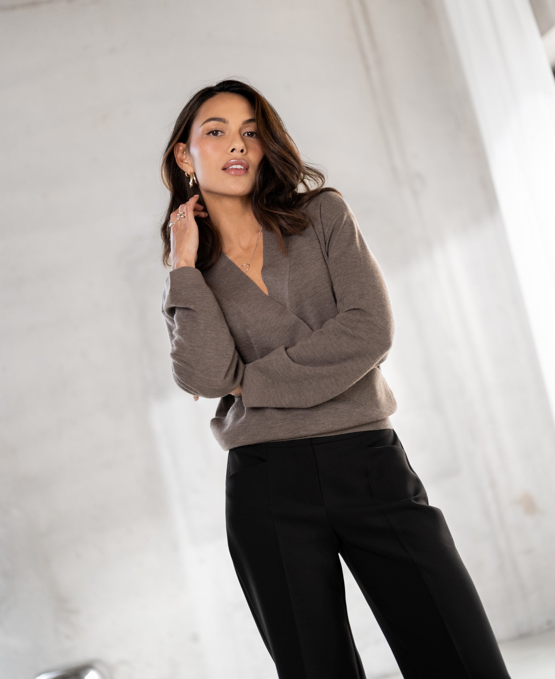 Woman wearing Taupe melange LES CINQ wrap sweater from PLEIN PUBLIQUE, shown indoors.