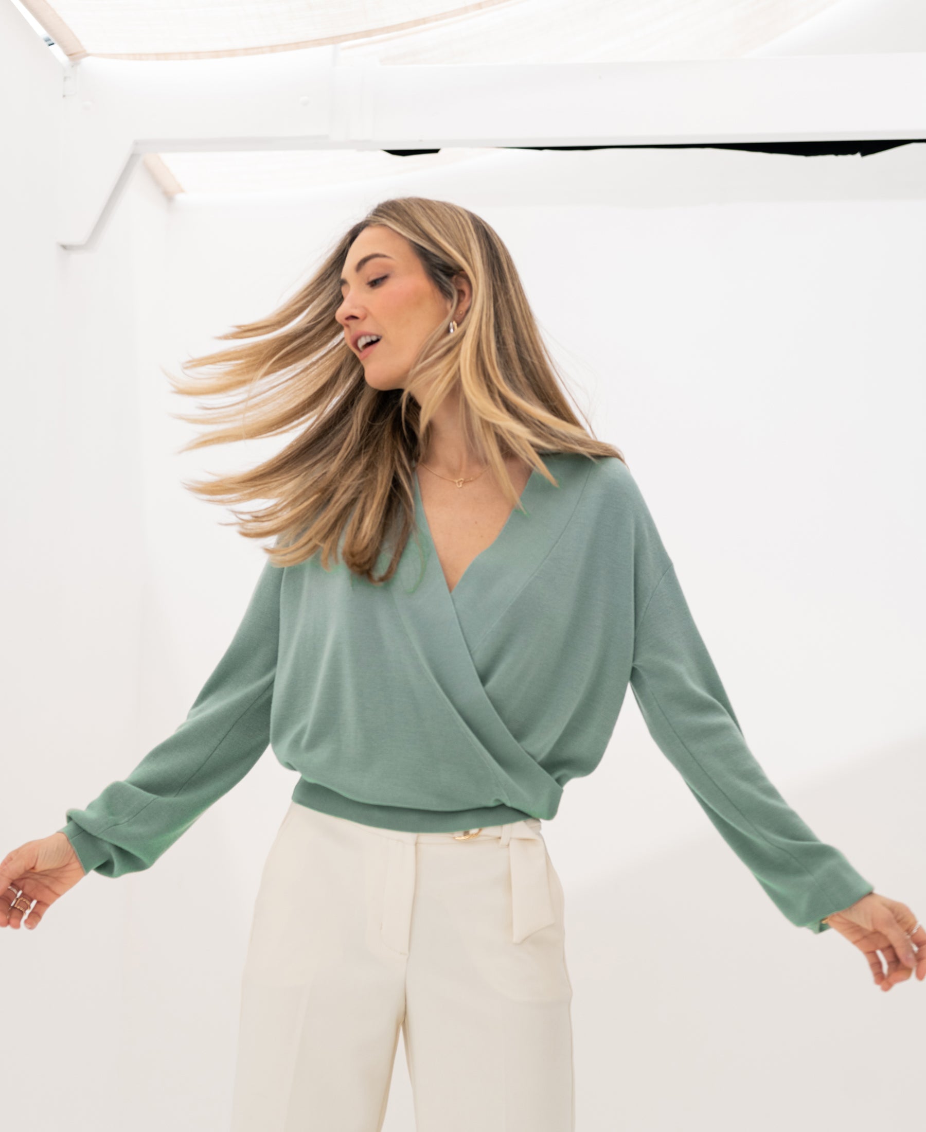 Sage green PLEIN PUBLIQUE wrap sweater in a bright white room.