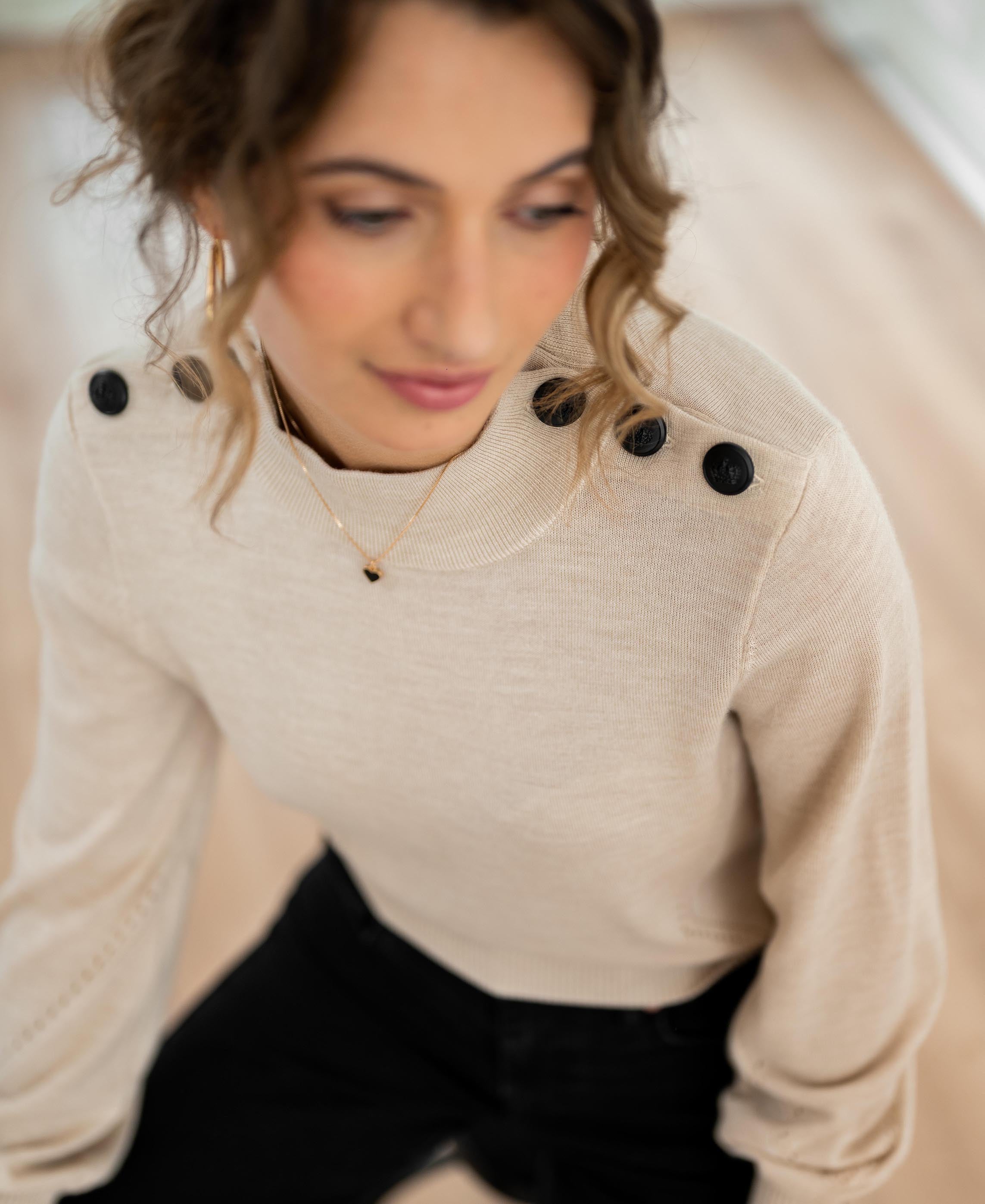 Merino wool sweater in sand with black shoulder buttons.