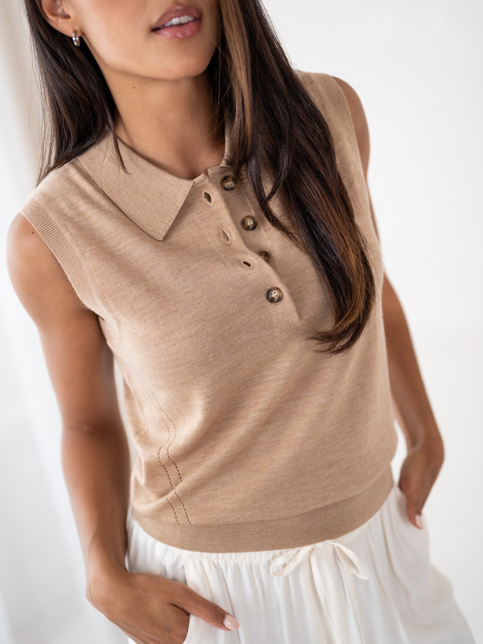 Sleeveless soft camel polo top by Plein Publique, shown on a woman with one hand in her pocket.