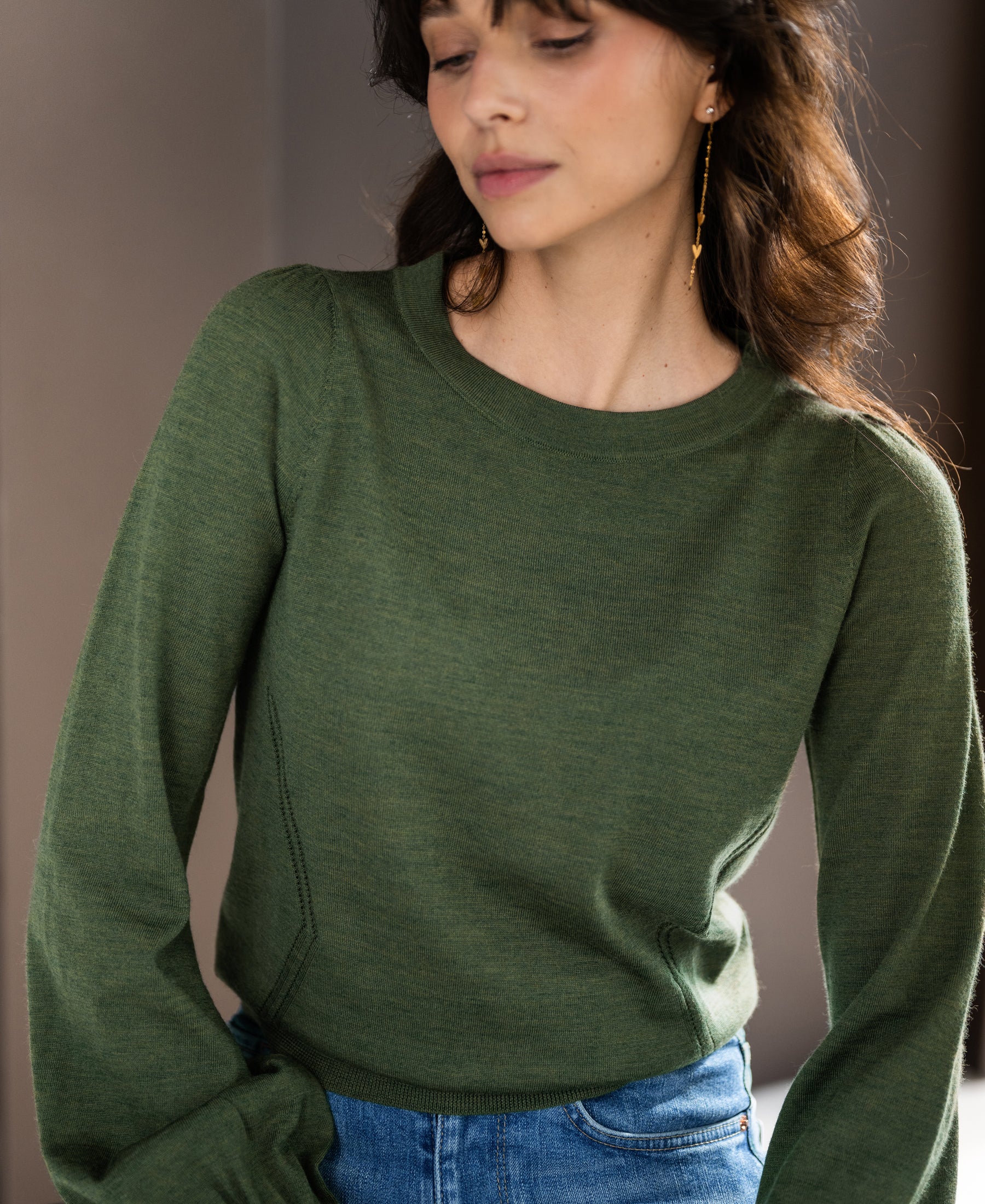 Woman wearing an olive green PLEIN PUBLIQUE Merino wool LA COEUR sweater.