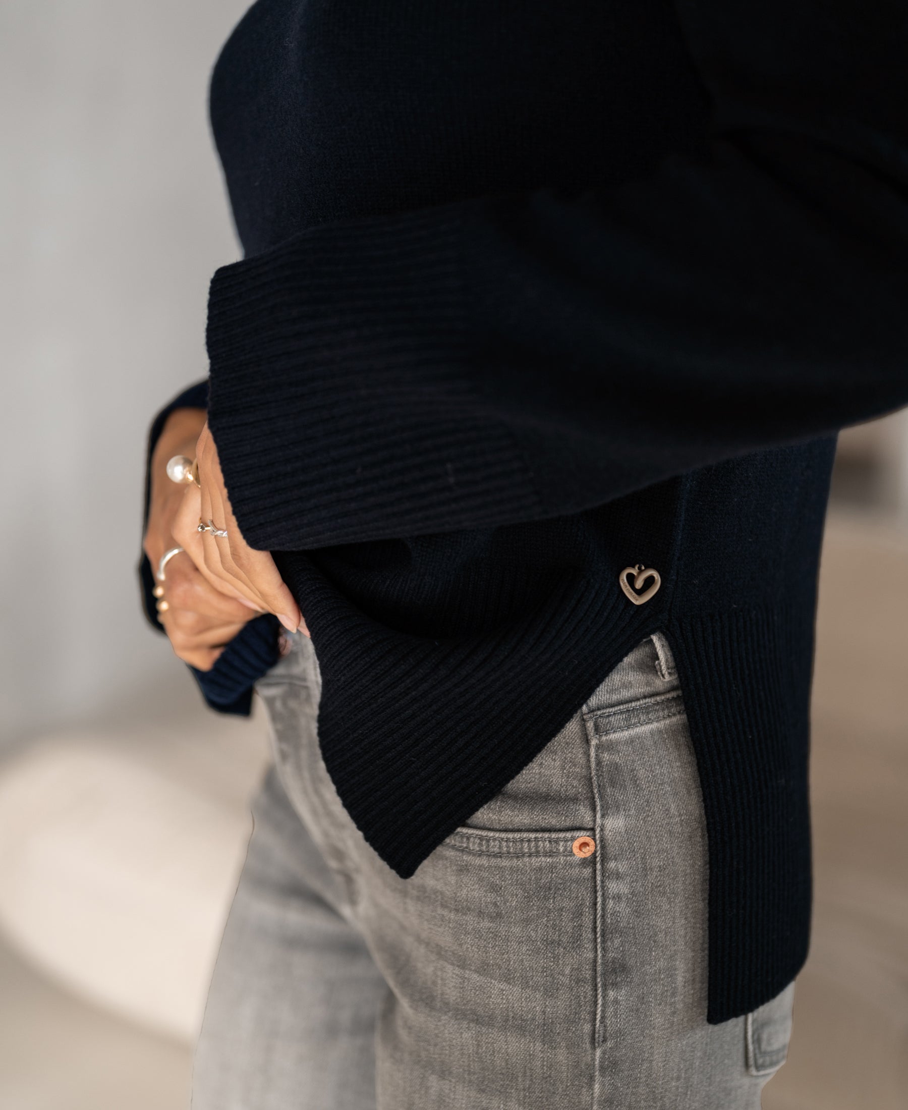 A person wearing a dark blue LA COZY turtleneck sweater from PLEIN PUBLIQUE.