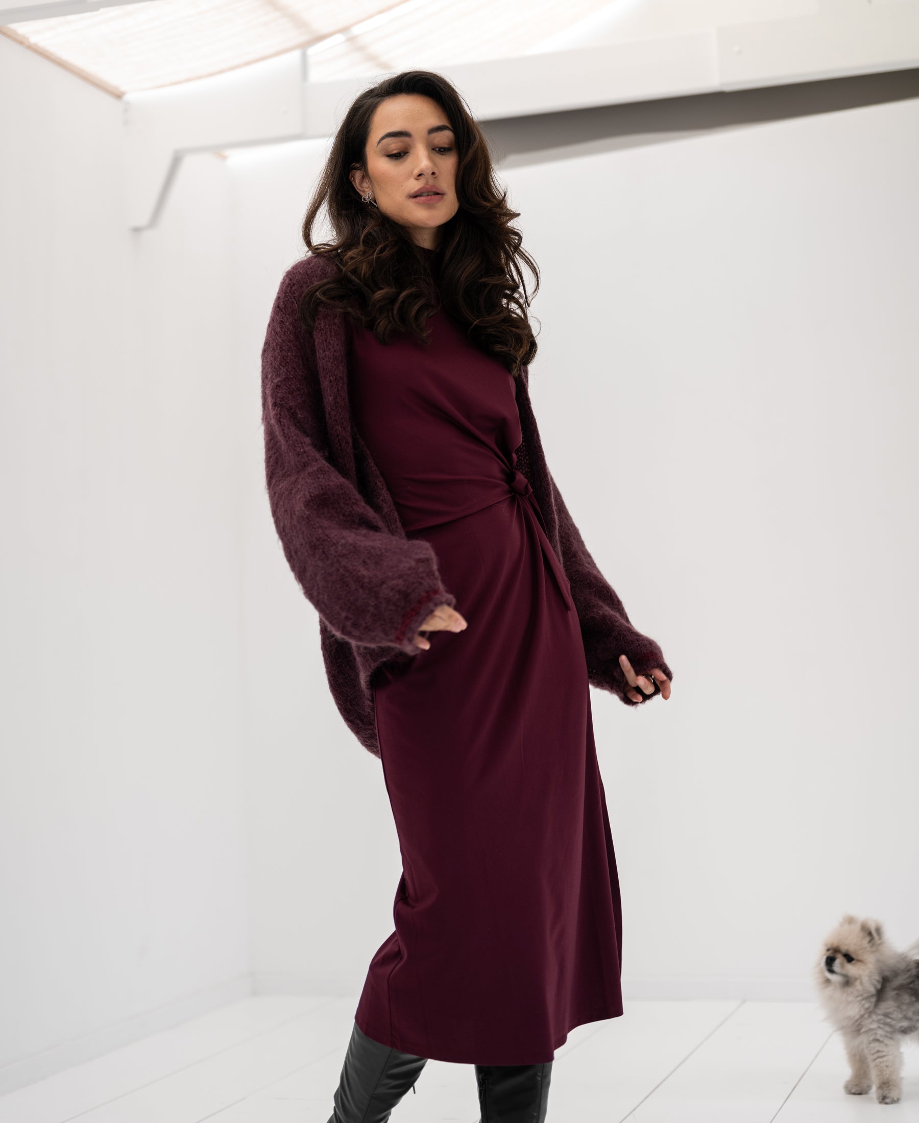 Woman wearing a Bordeaux LA TOULOUSE travel dress by OVERIG stands indoors.