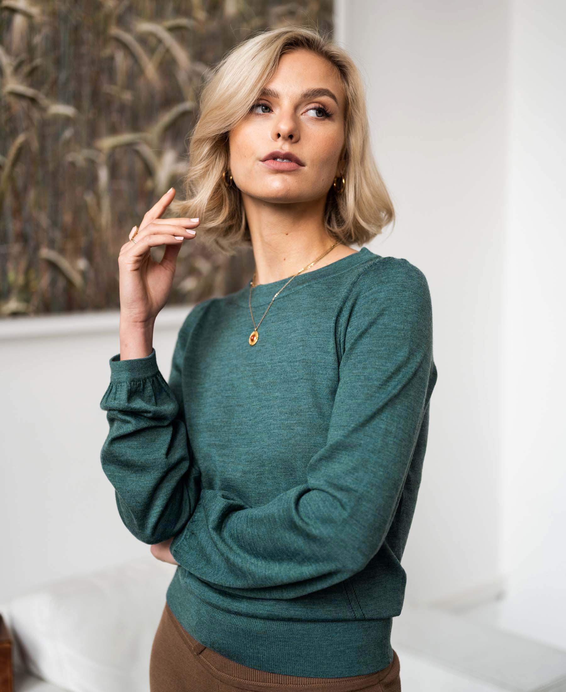 Green merino wool sweater LA COEUR by PLEIN PUBLIQUE, shown indoors.