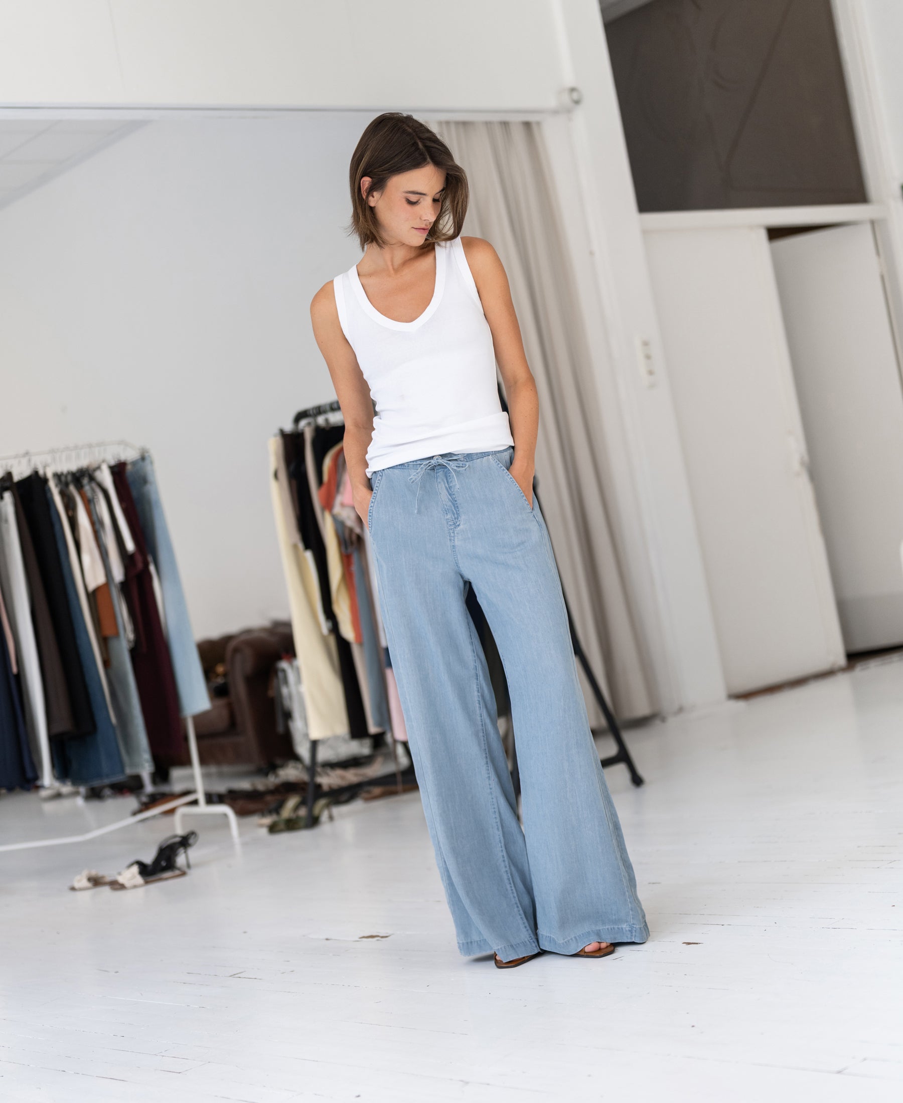 Woman wears light blue Tencel denim jeans called LE DEGAS by PLEIN PUBLIQUE; product shown from the front.