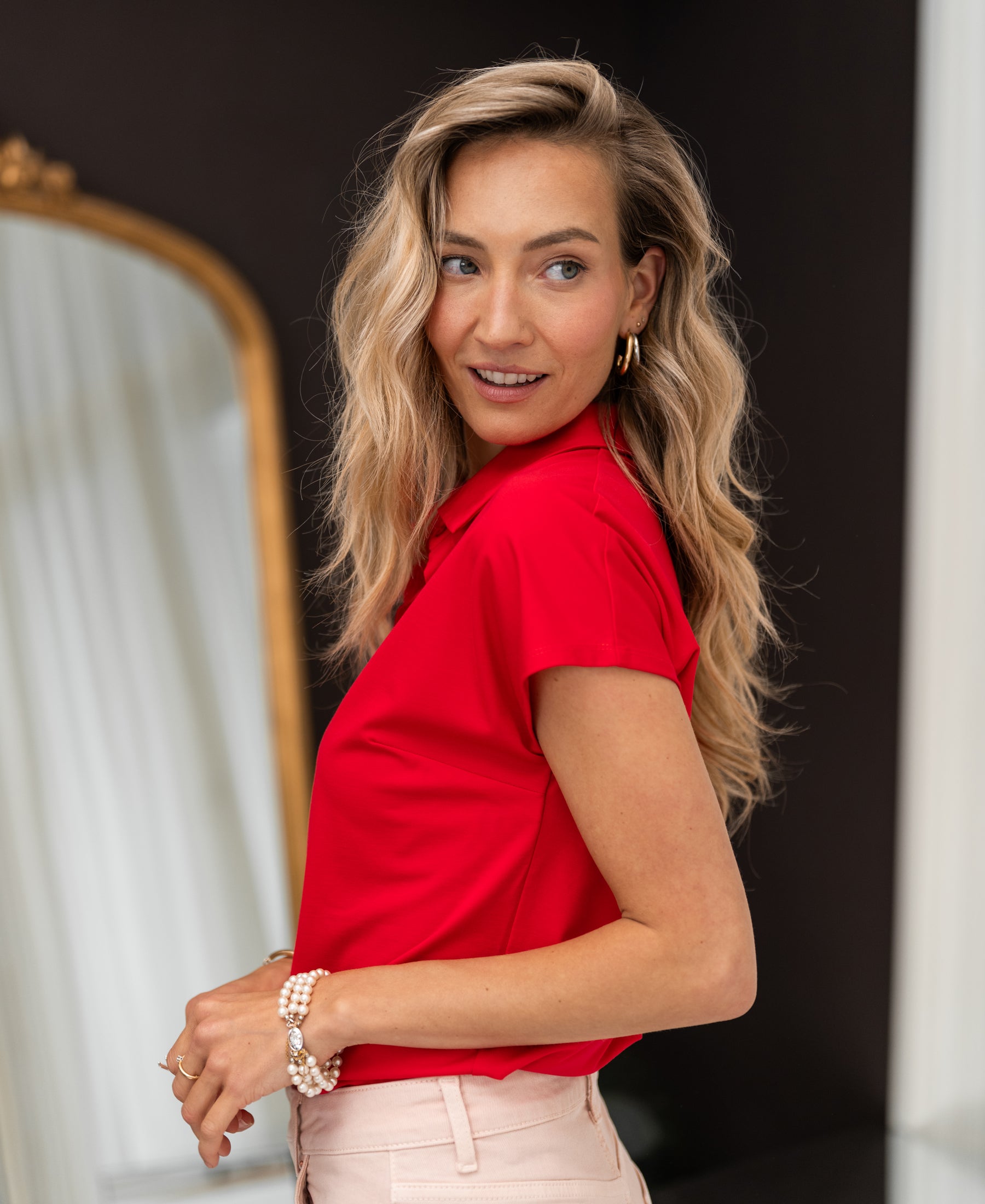 Red travel blouse by PLEIN PUBLIQUE LA DELON shown in a softly lit room.