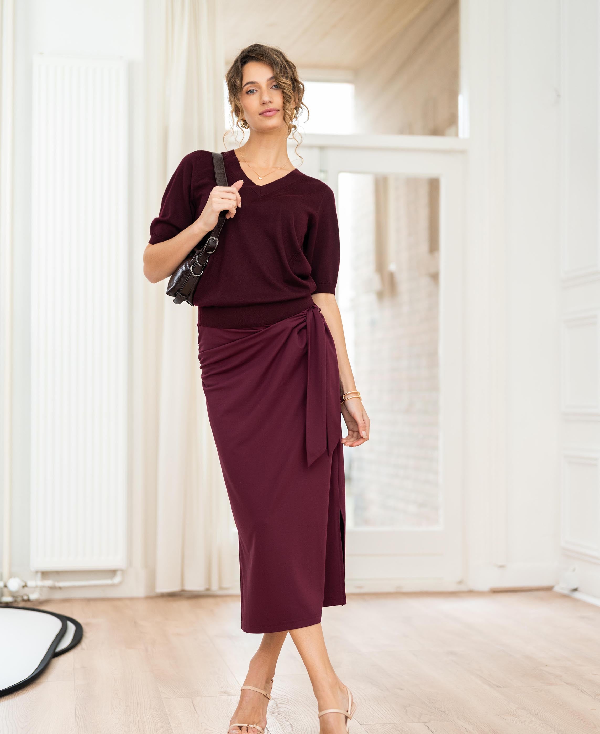 Burgundy Travel Skirt LE MAEL by PLEIN PUBLIQUE shown in a bright room with wooden floors.
