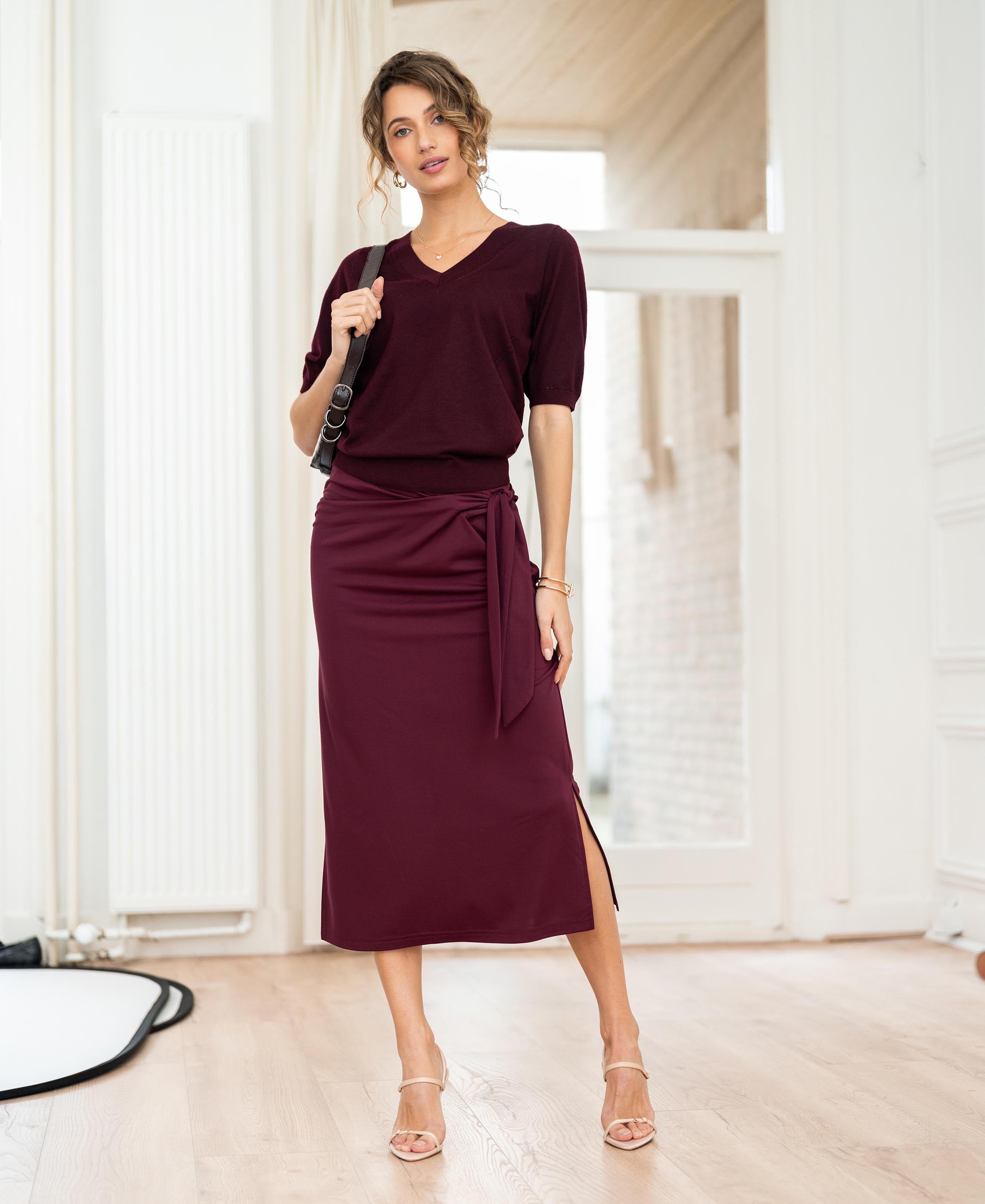 Travel Skirt LE MAEL in Wine by PLEIN PUBLIQUE shown in a bright modern room.