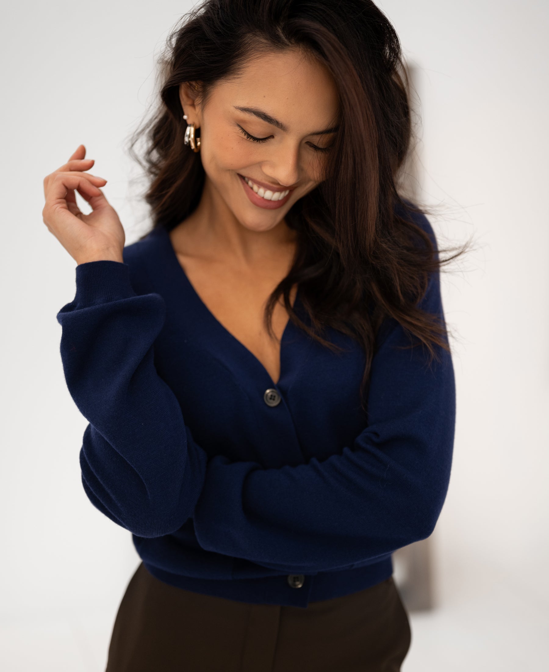 Woman wearing a navy Merino wool vest looks down with eyes closed.