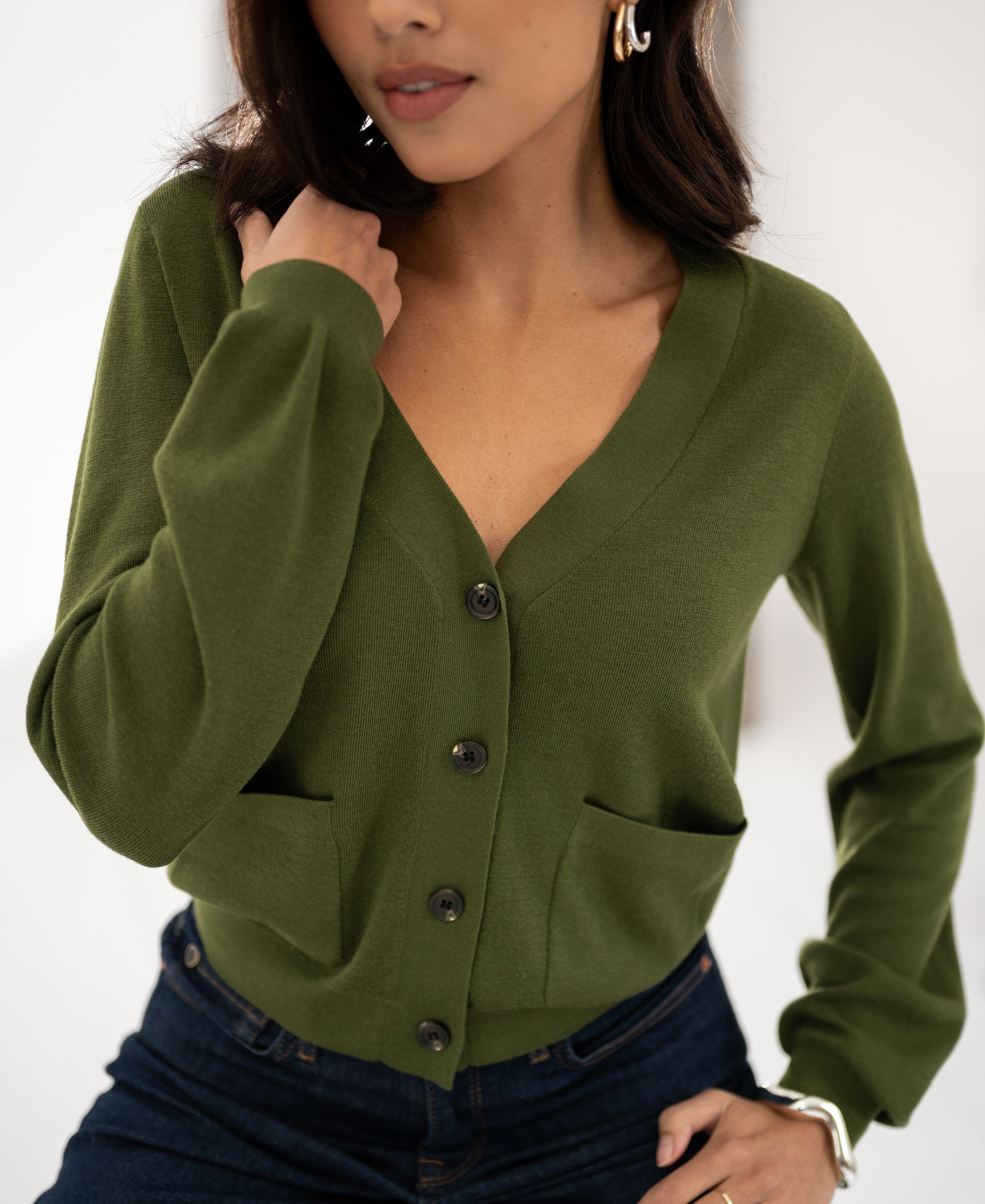 Woman wearing PLEIN PUBLIQUE Merino wool cardigan LA DONNA in olive, hand on shoulder and hip.