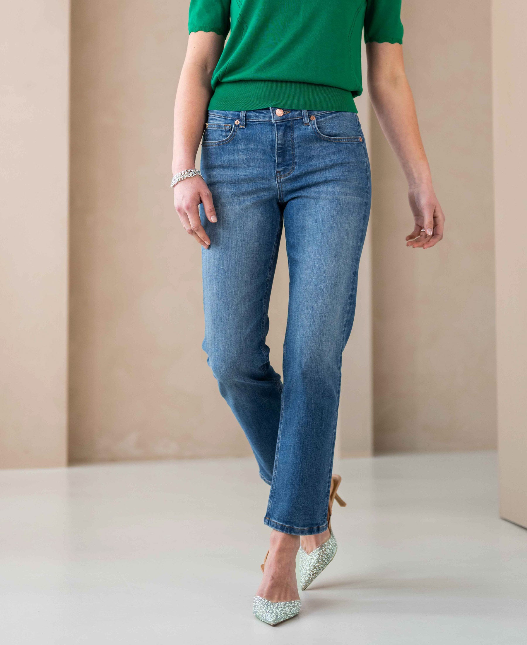 Woman wearing stonewash cropped jeans on a beige background.