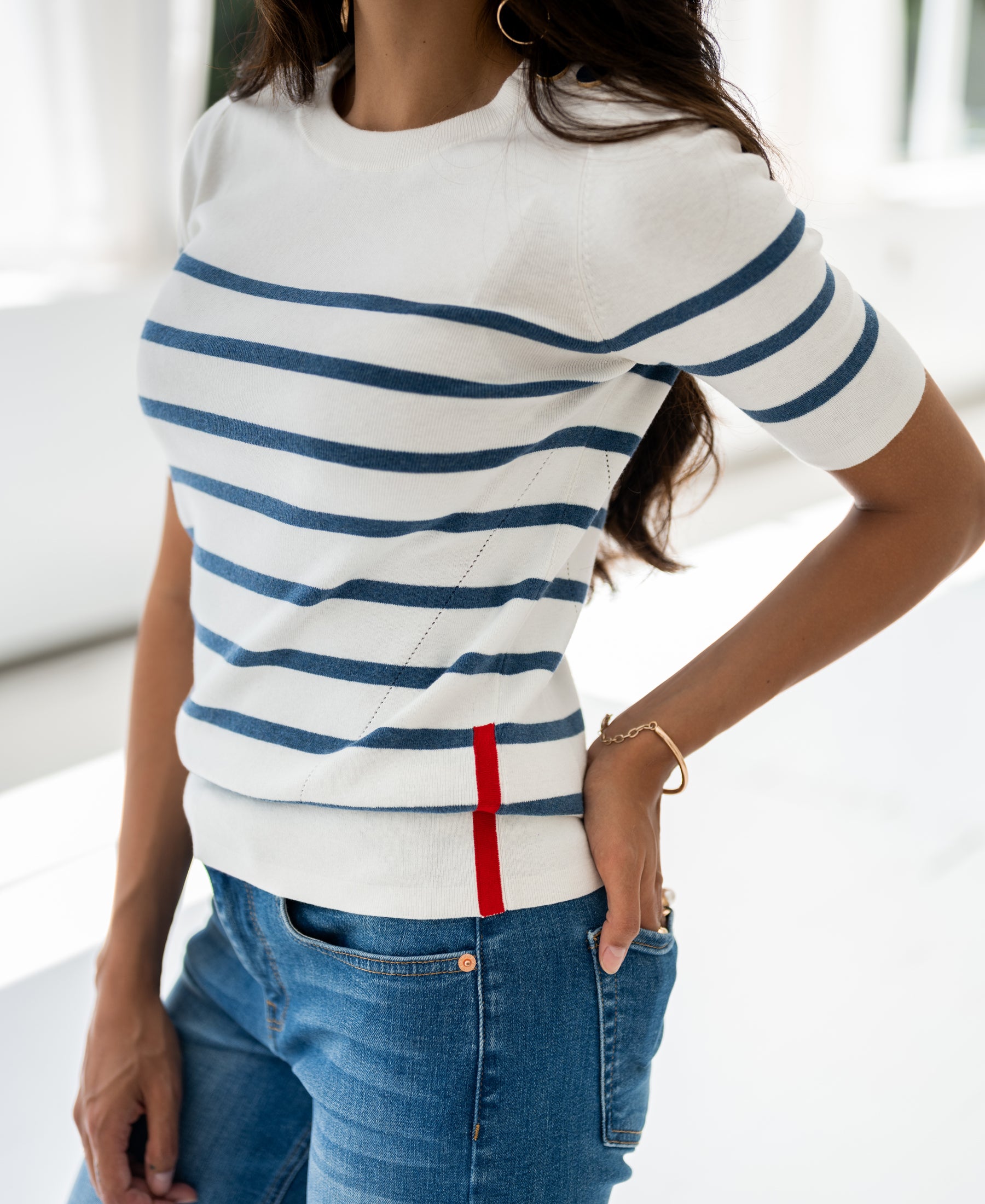 Ivory and denim blue Breton stripe sweater by PLEIN PUBLIQUE, long sleeves, modeled with one hand in pocket.