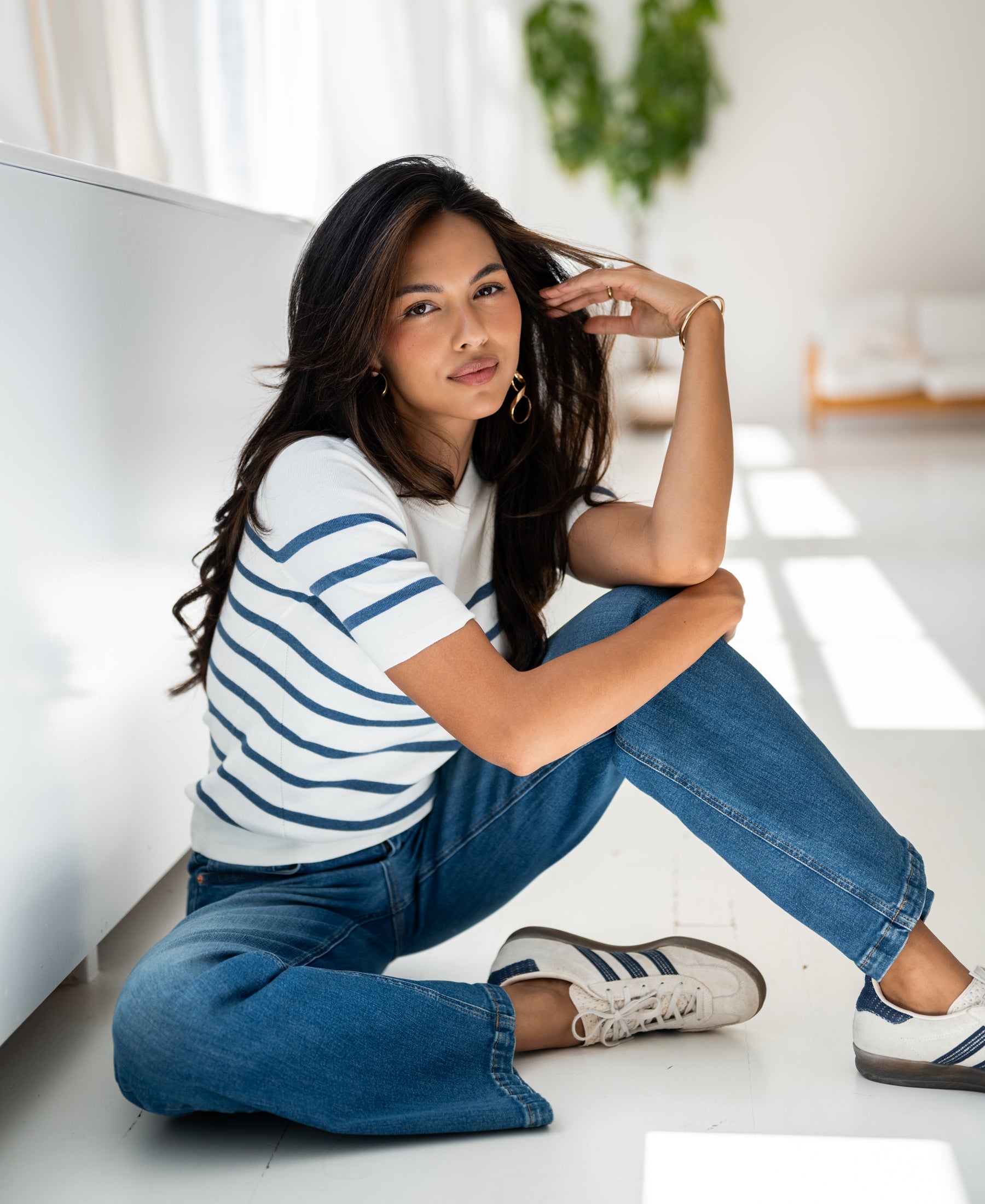 Woman wears the PLEIN PUBLIQUE Breton striped sweater ESISA in ivory and denim blue, shown indoors.