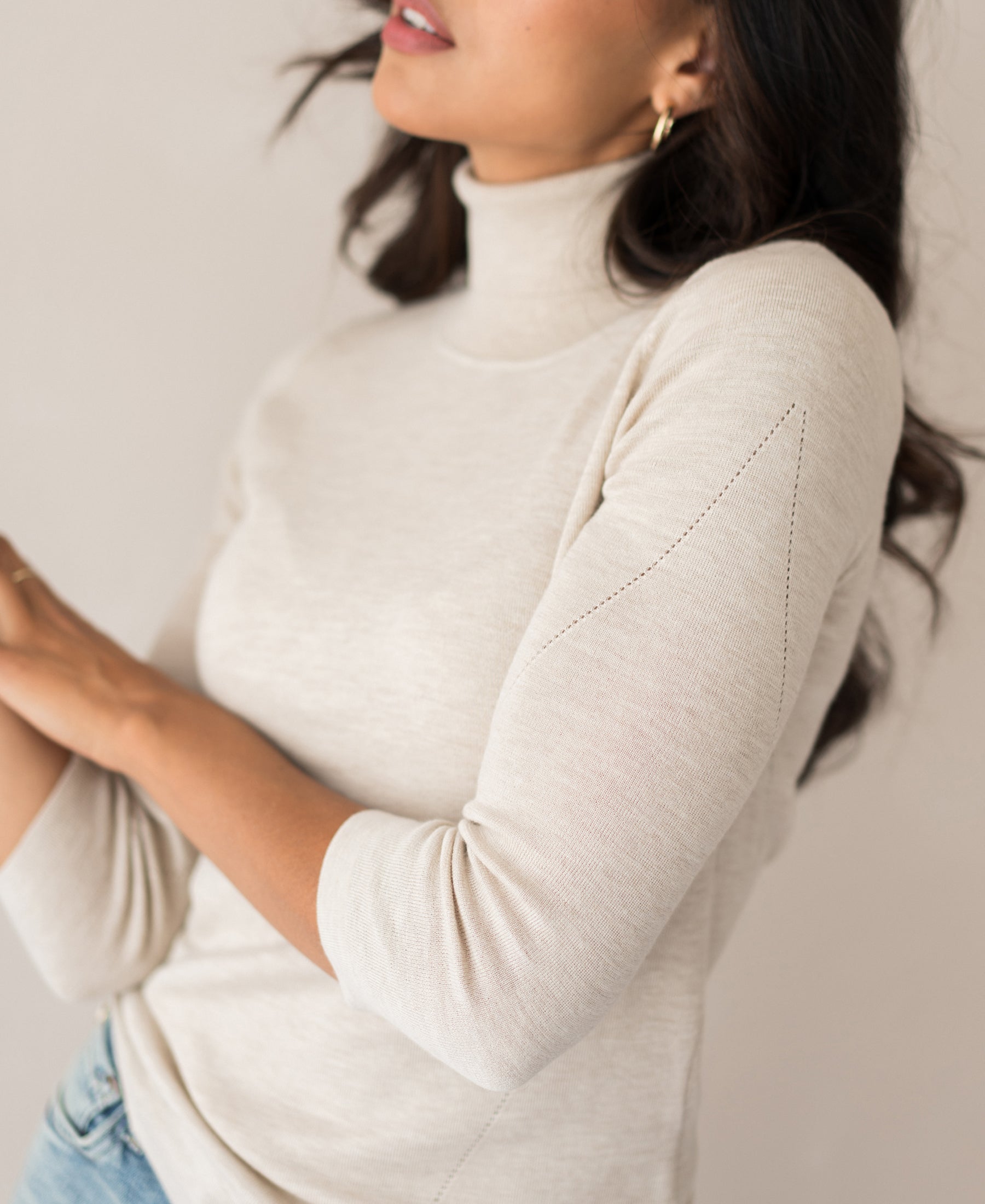 Beige turtleneck sweater in a ribbed knit, shown on a model against a neutral background.