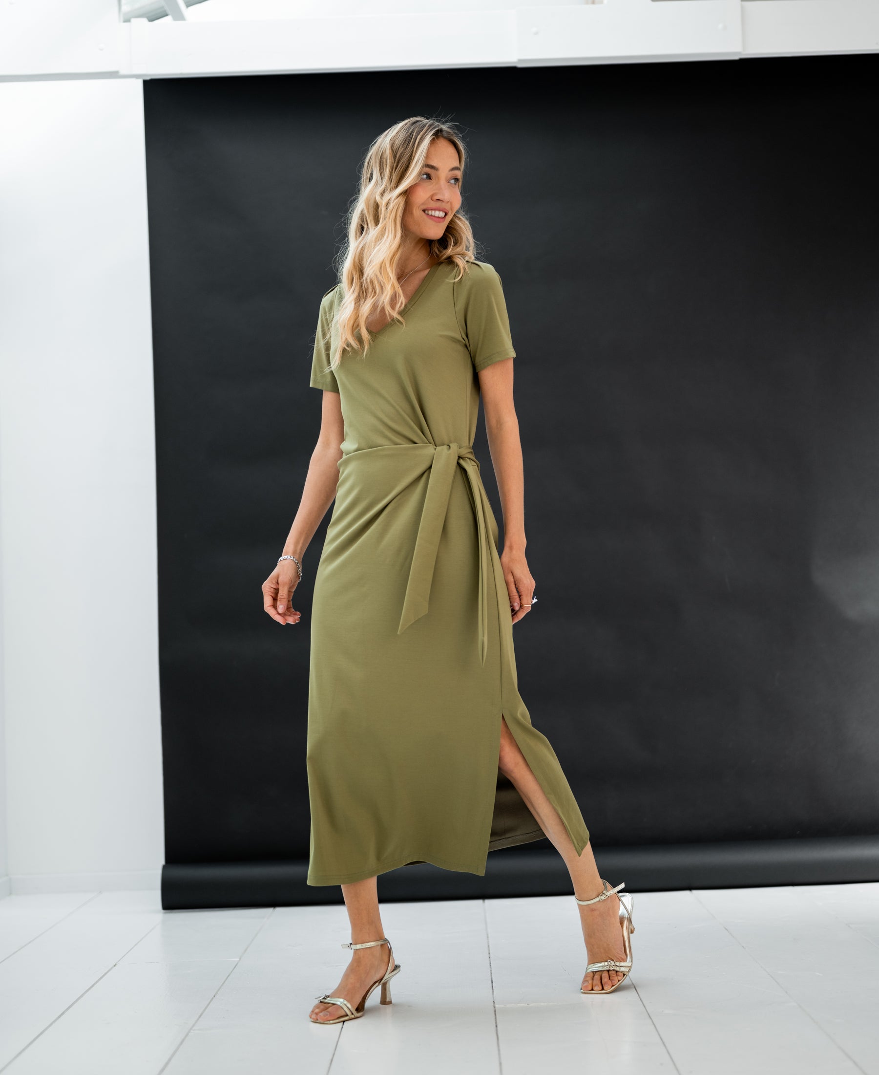 Long dress LA FILICIA in olive green by PLEIN PUBLIQUE, shown against a black backdrop.
