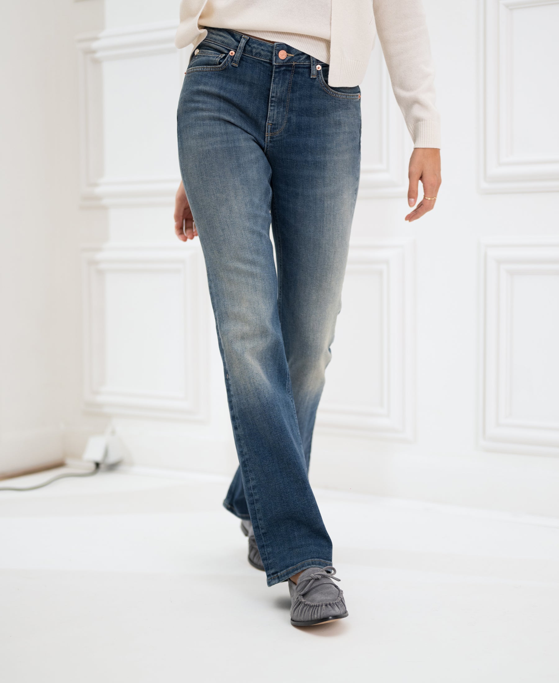 Blue vintage flared jeans by PLEIN PUBLIQUE, shown worn by a model standing in a white room.