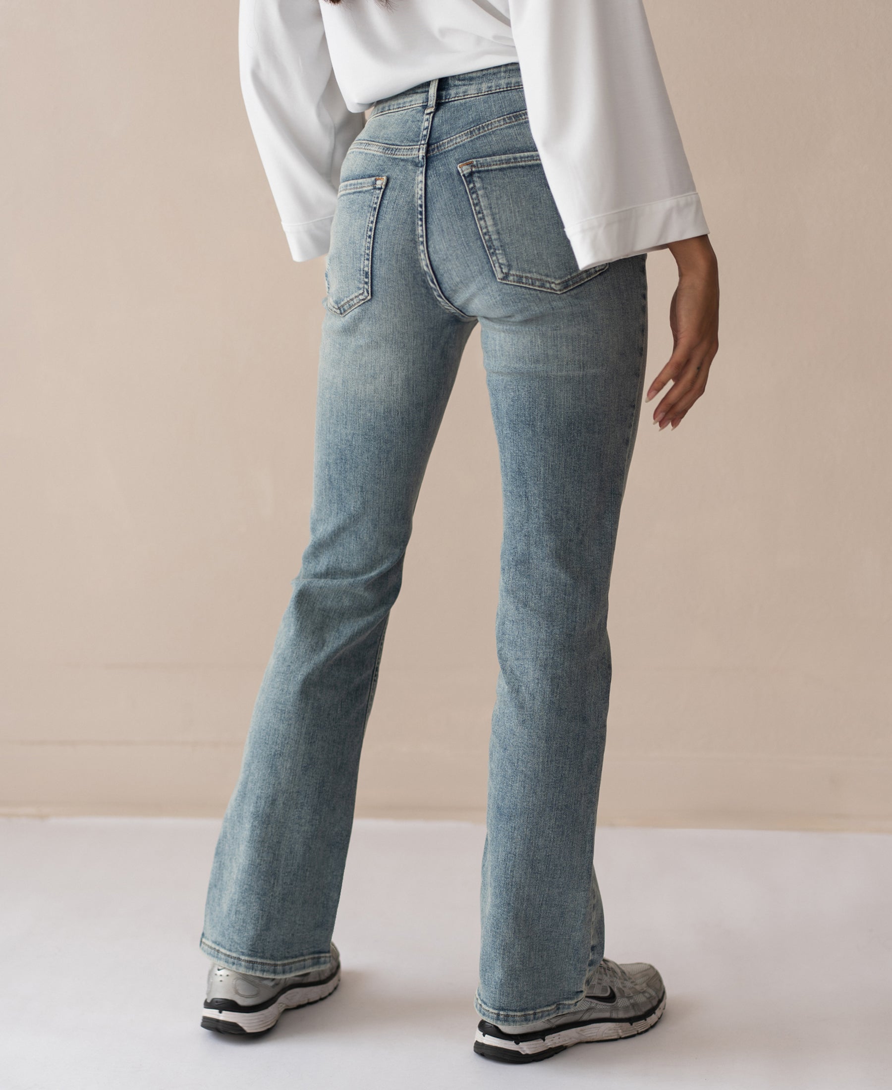 Person wearing vintage wash flared jeans, seen from the back.