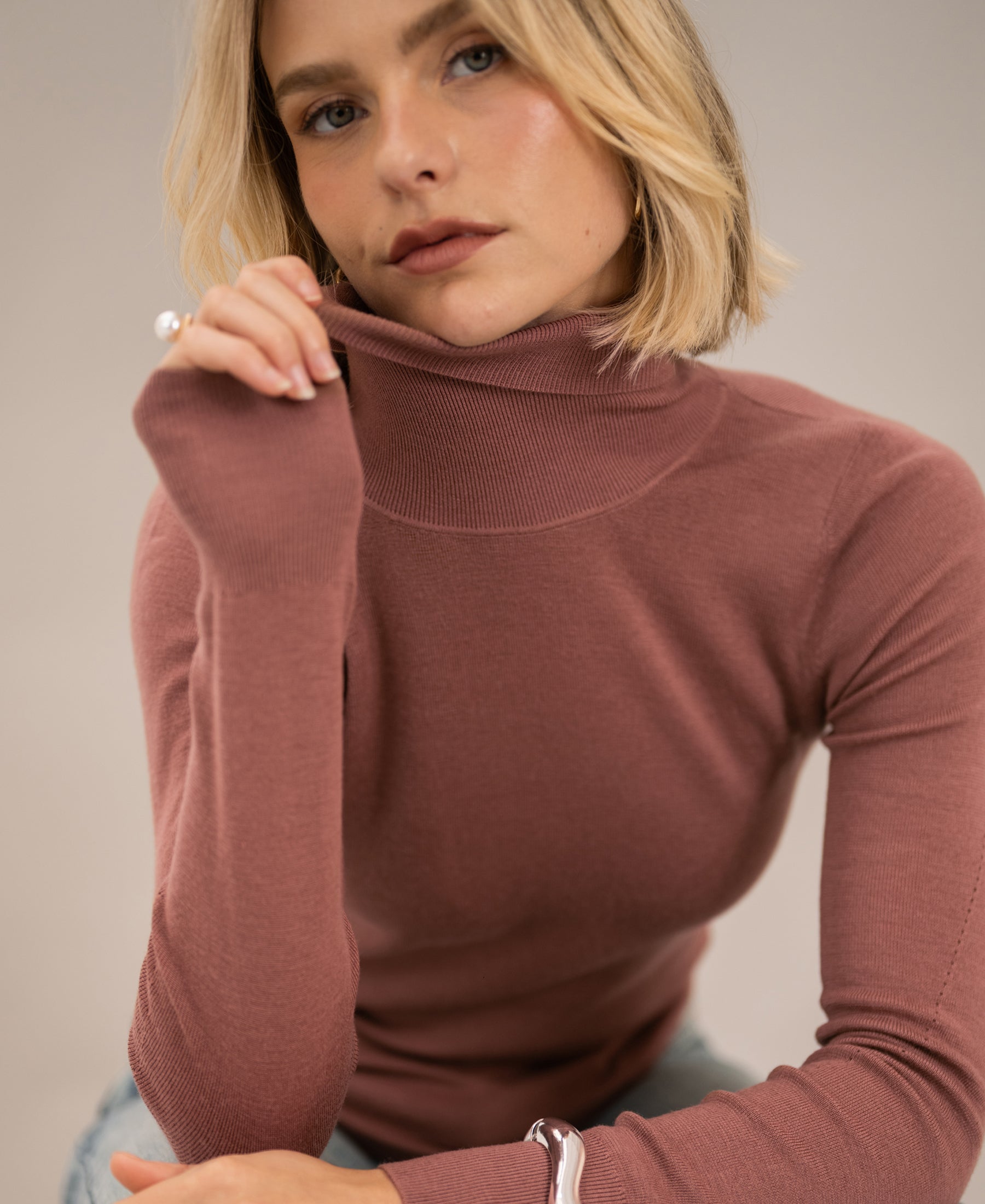 Dusty pink merino wool turtleneck sweater, shown from the front.