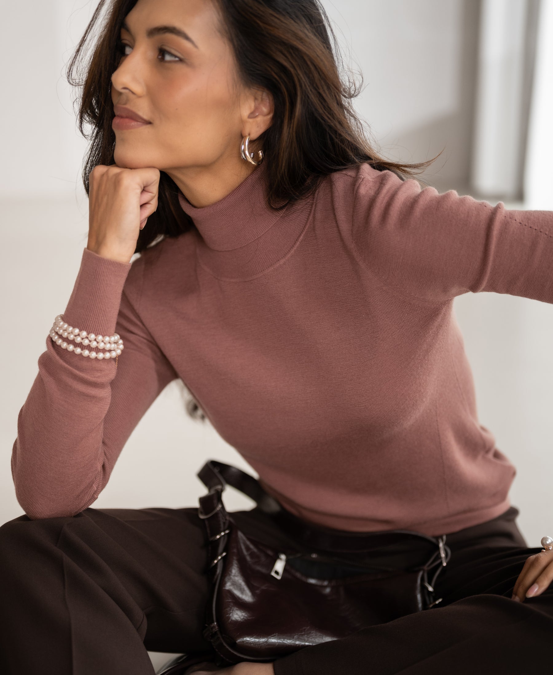 Woman wearing a dusty pink merino wool turtleneck sweater.