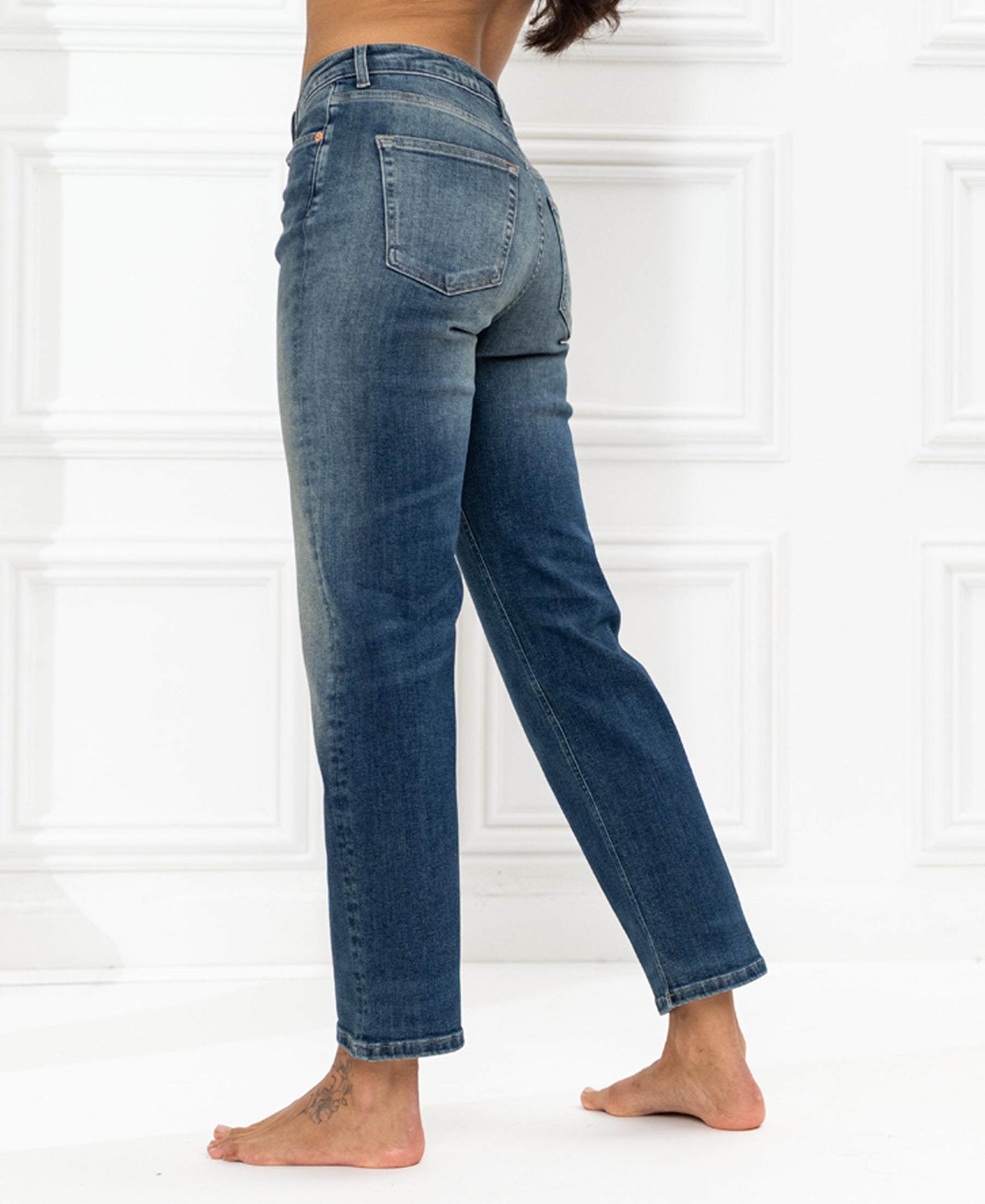 Back view of blue vintage cropped jeans in a classic fit, shown against a white wall.
