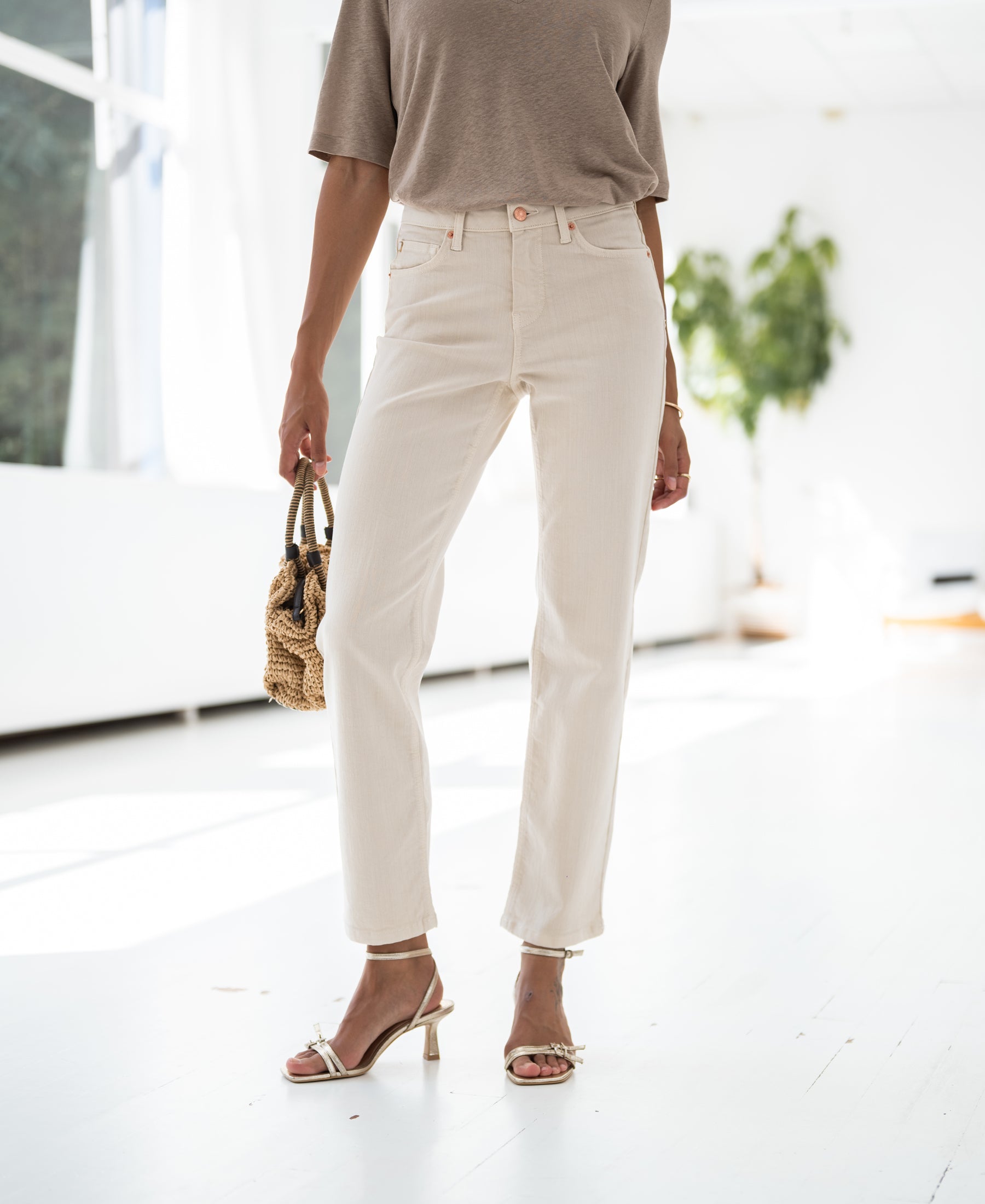 Woman wearing cream cropped jeans in a minimalist room.