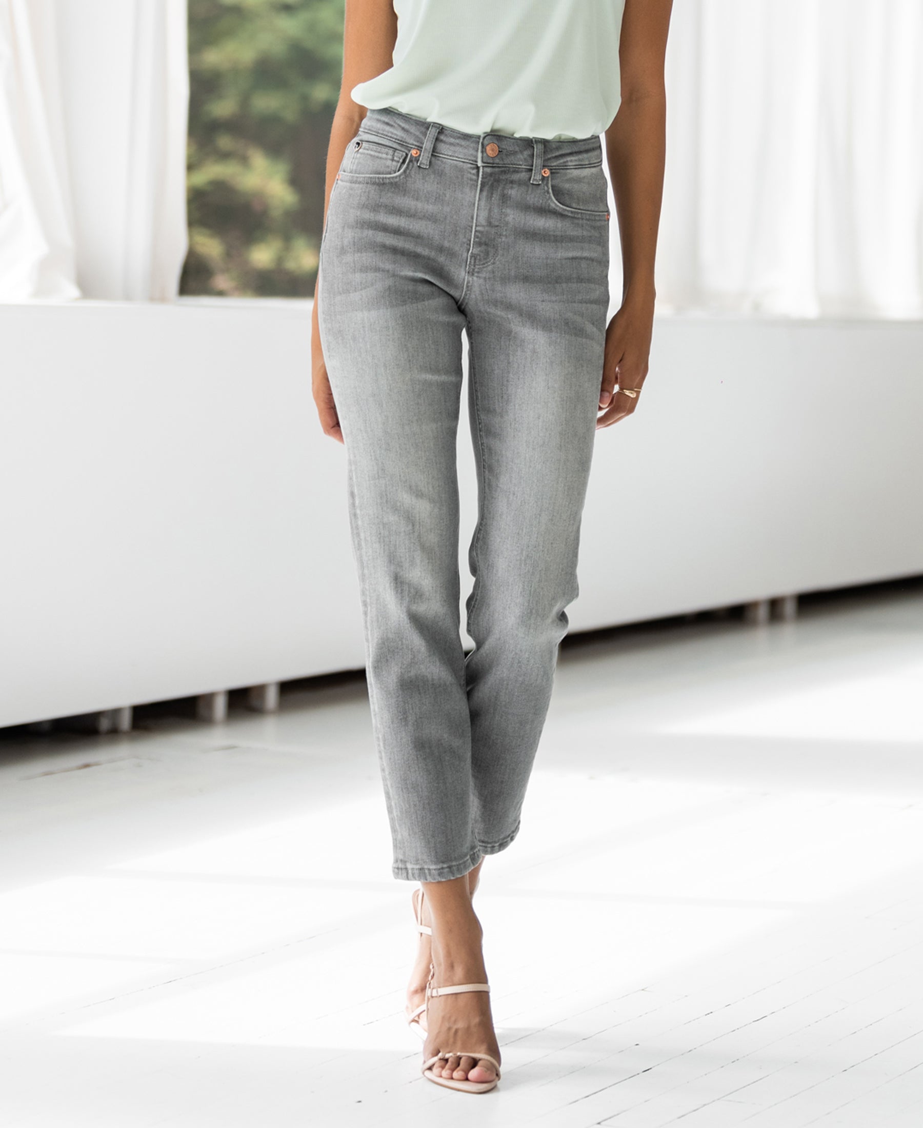 Grey stonewash cropped jeans in a bright room with large windows.
