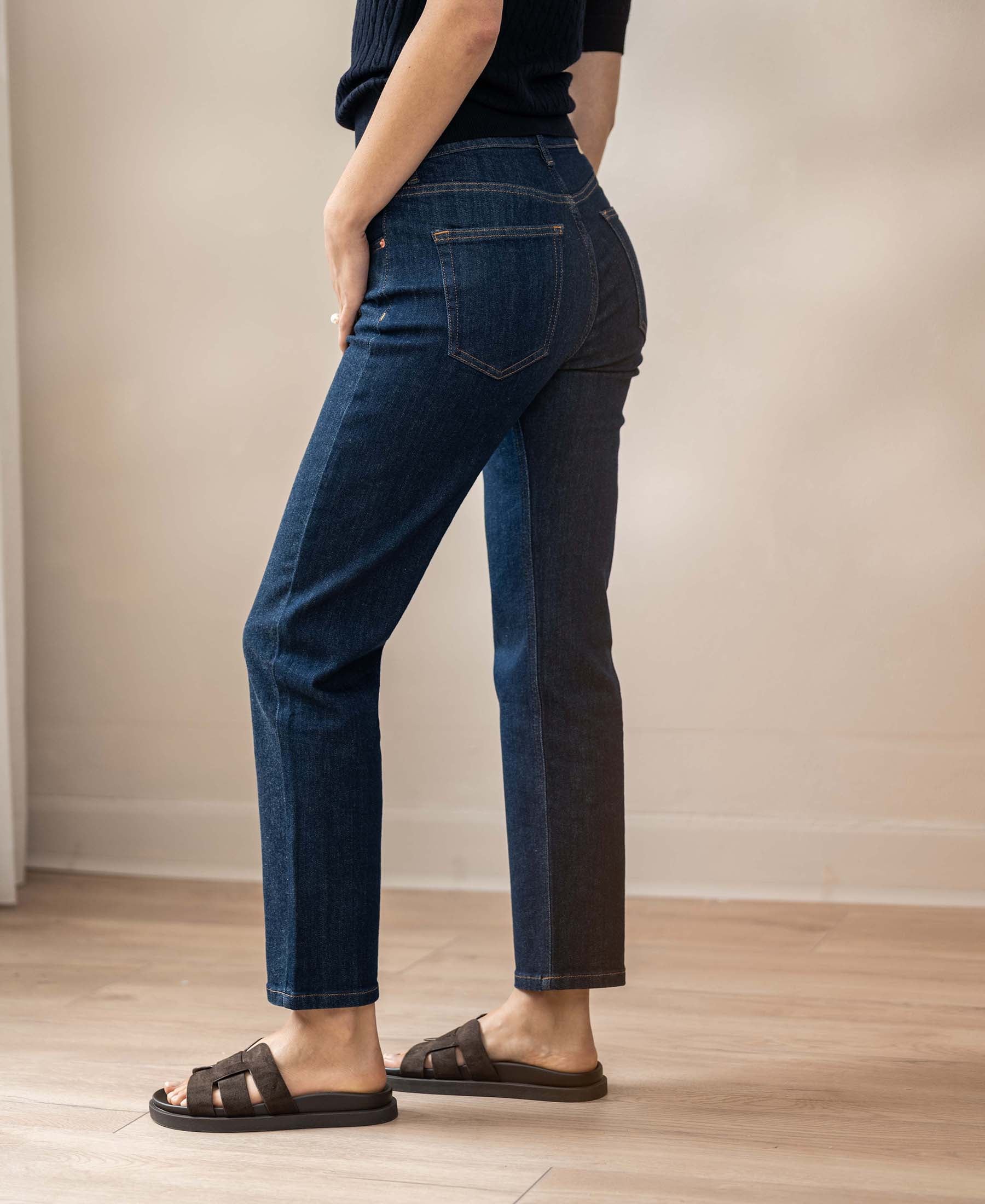 A person models cropped blue rinse wash jeans on a light wood floor.