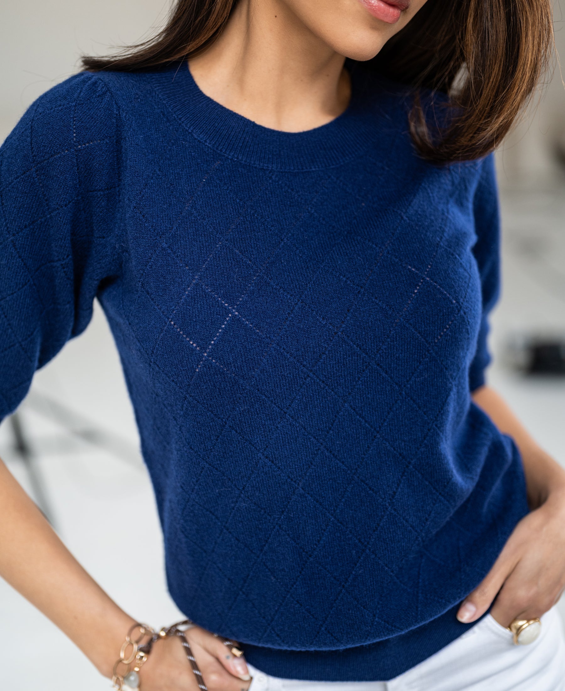 Woman wearing the Argyle merino wool sweater LE HARVARD Navy by PLEIN PUBLIQUE, standing indoors.