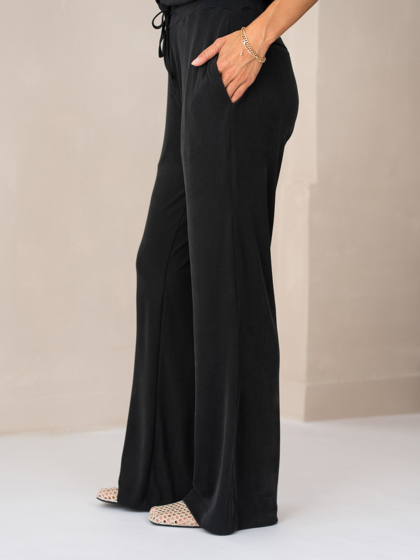 Charcoal lounge pants in a relaxed fit, modeled with one hand in the pocket.