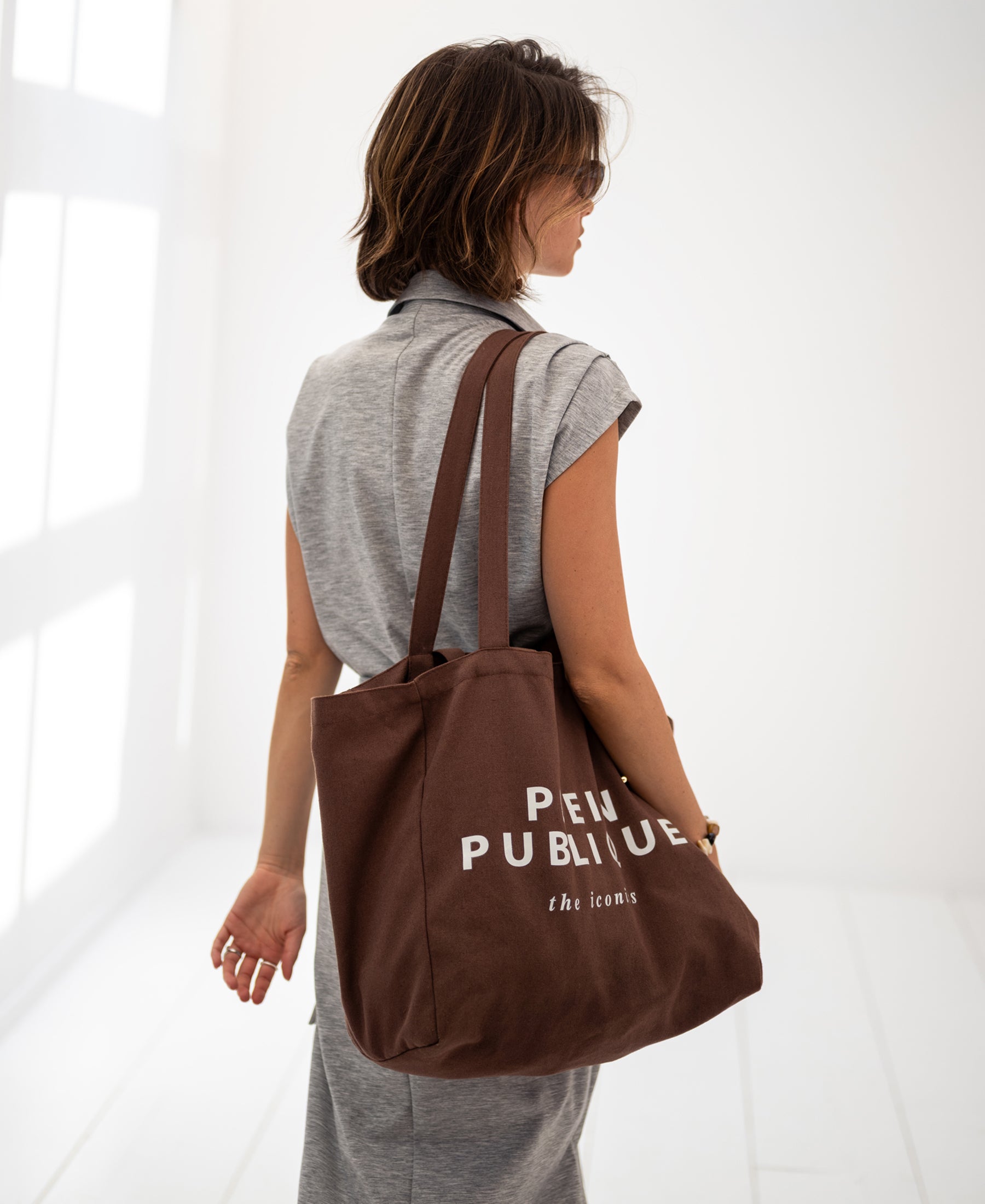 Brown canvas tote bag shown in a bright, minimalist room.