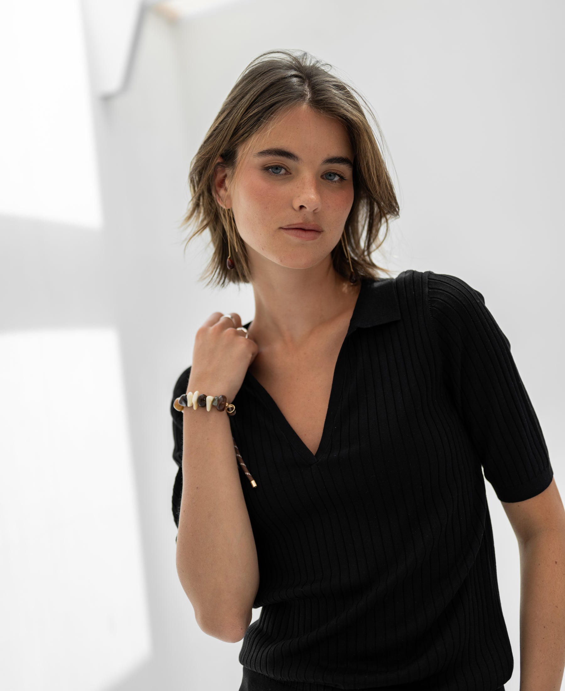 Black Tencel-silk LE JASMIN polo shirt by PLEIN PUBLIQUE, shown indoors.