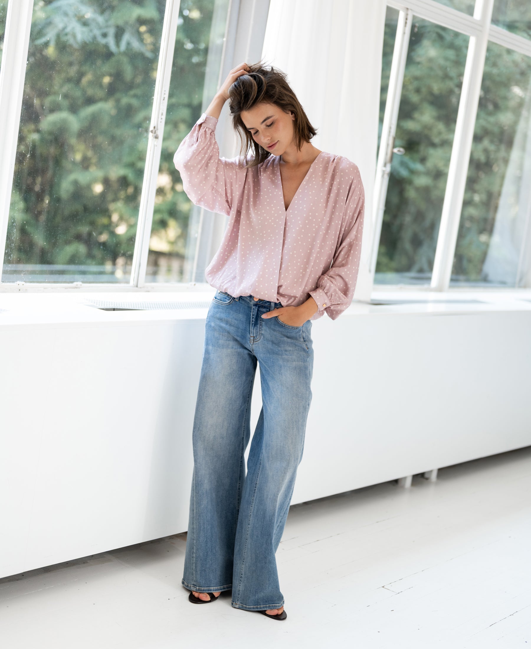 Dusty pink polka dot blouse in a bright room.