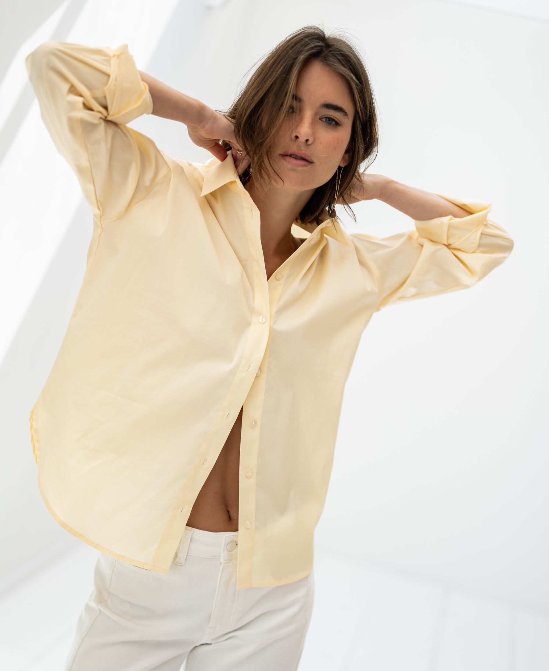 Oversized easy-iron blouse in soft yellow, shown in a bright, minimalist room.
