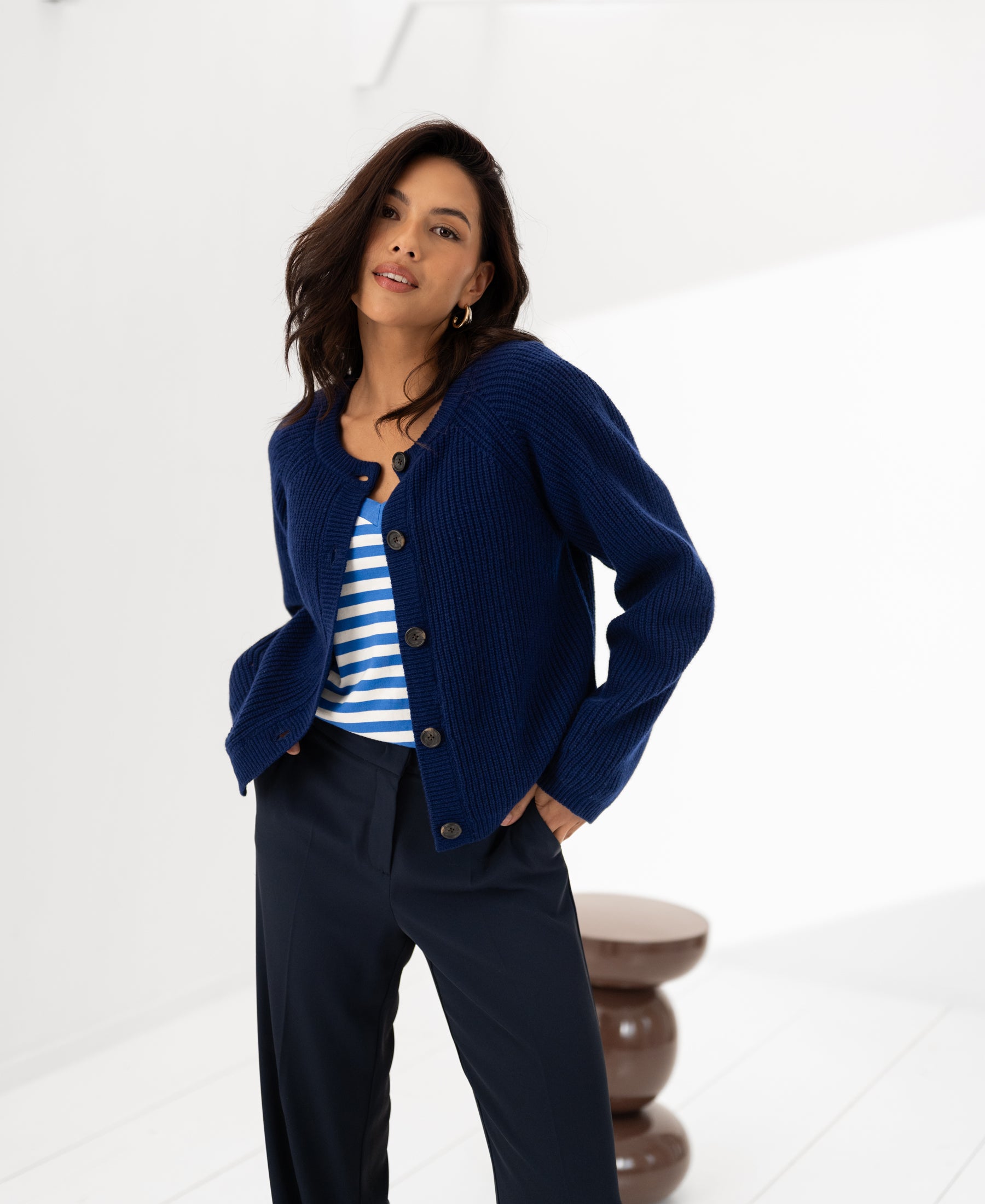 Woman wearing a navy merino wool vest in a bright white room.
