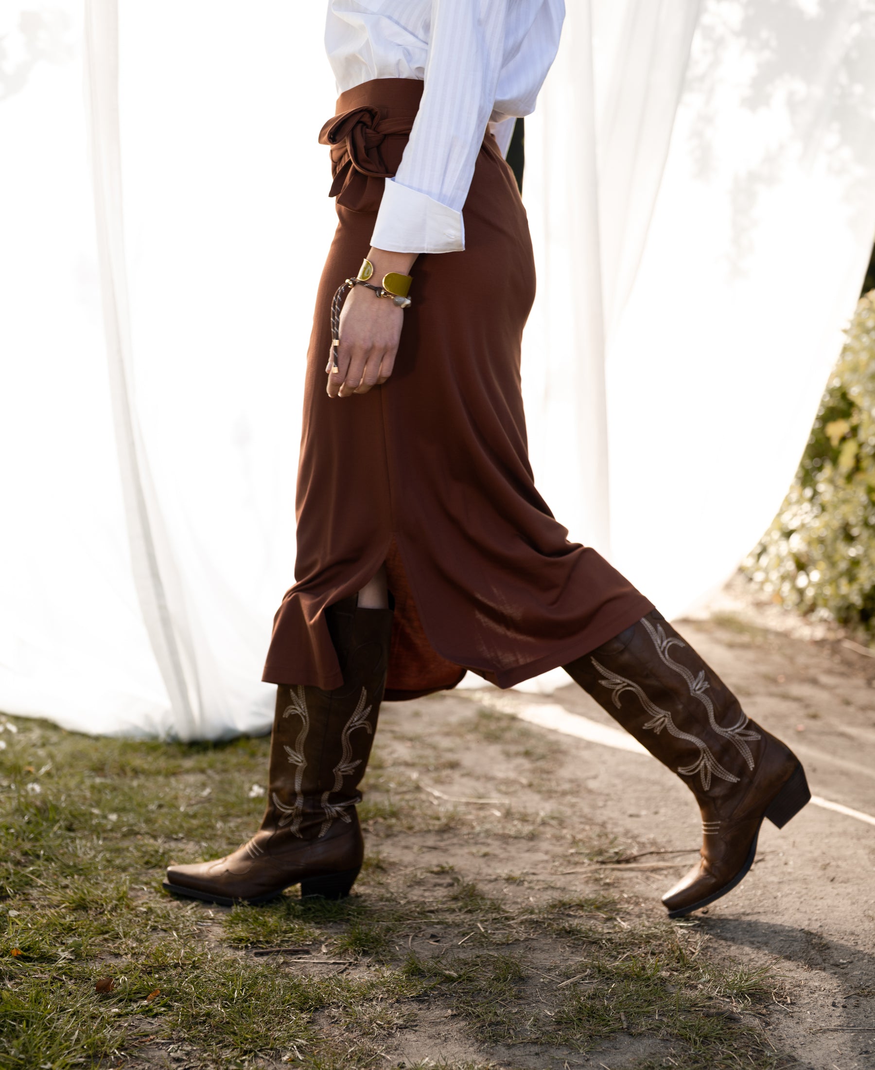 Camel-colored travel skirt by Plein Publique, shown outdoors.
