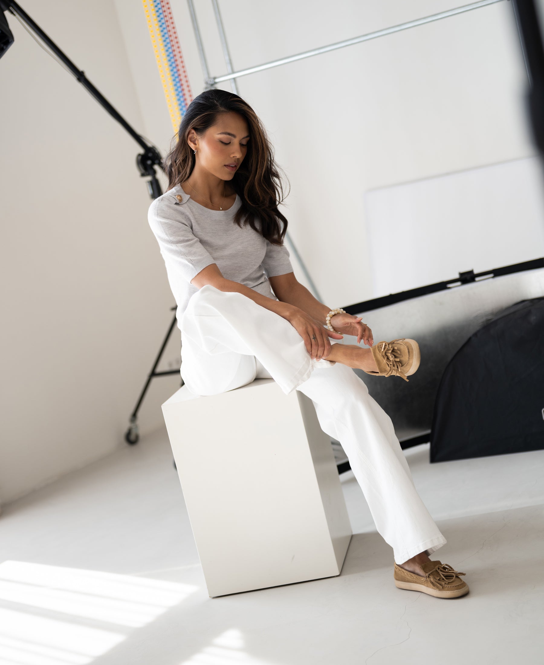 Woman wearing PLEIN PUBLIQUE LE MAJOR silver grey Merino wool sweater in a bright studio.