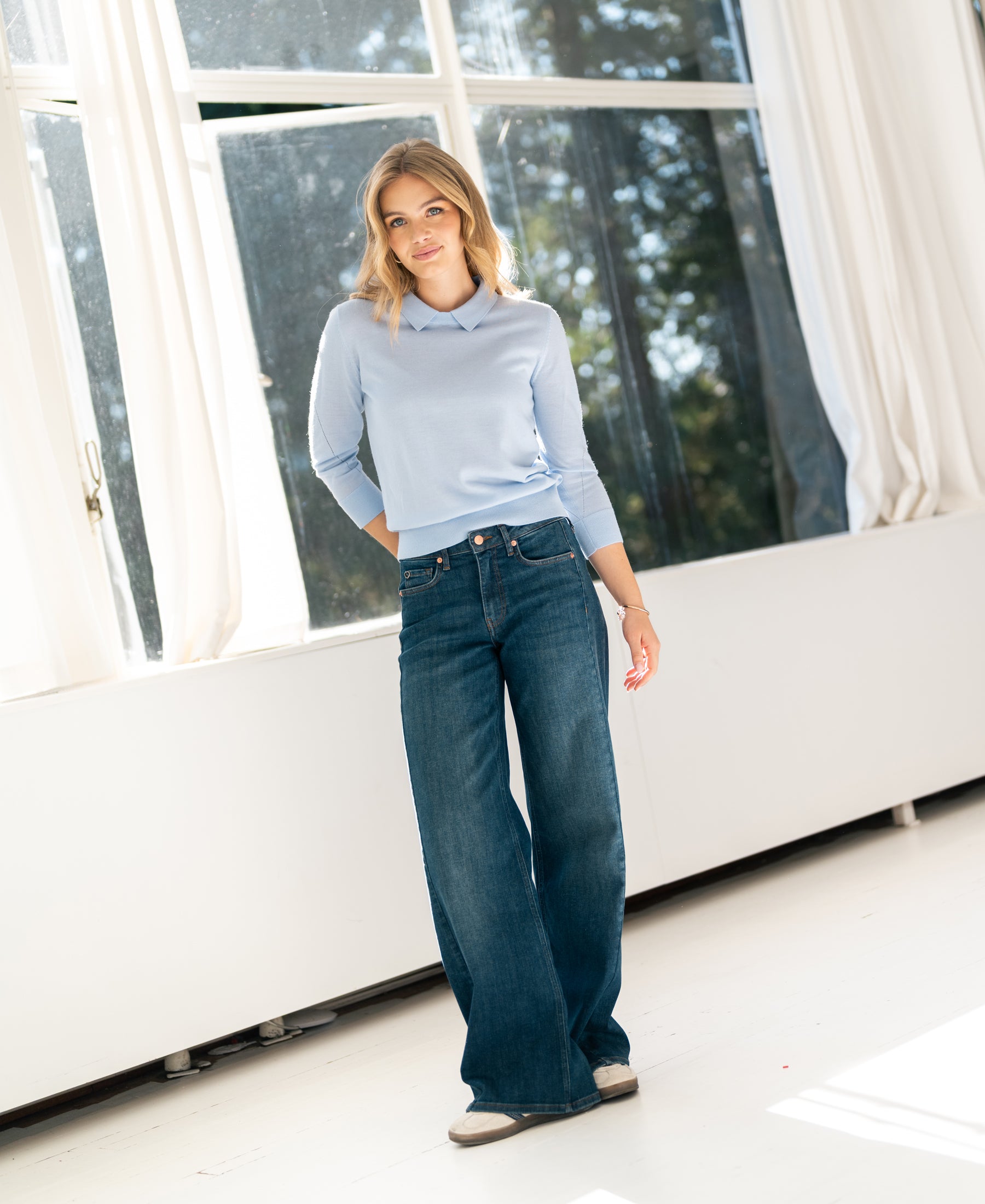 Wide leg blue heritage jeans in LE SPICE style, worn by a woman standing in a bright room.
