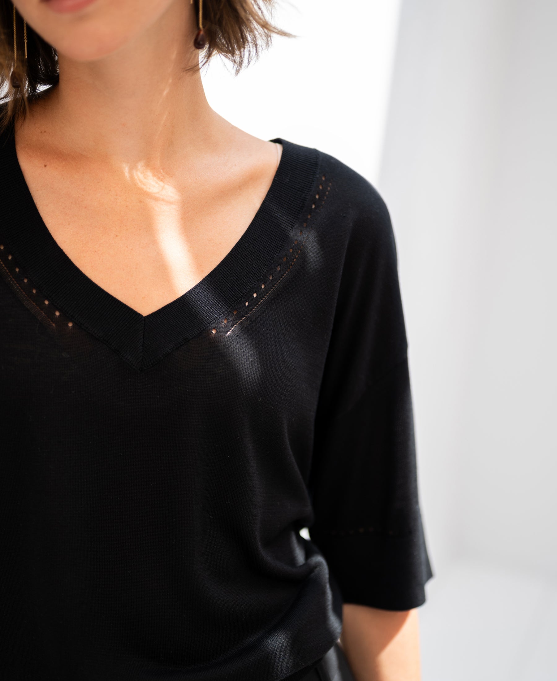 Black silk blend LE MARDY top by PLEIN PUBLIQUE, shown in bright light, front view, models face partly out of frame.