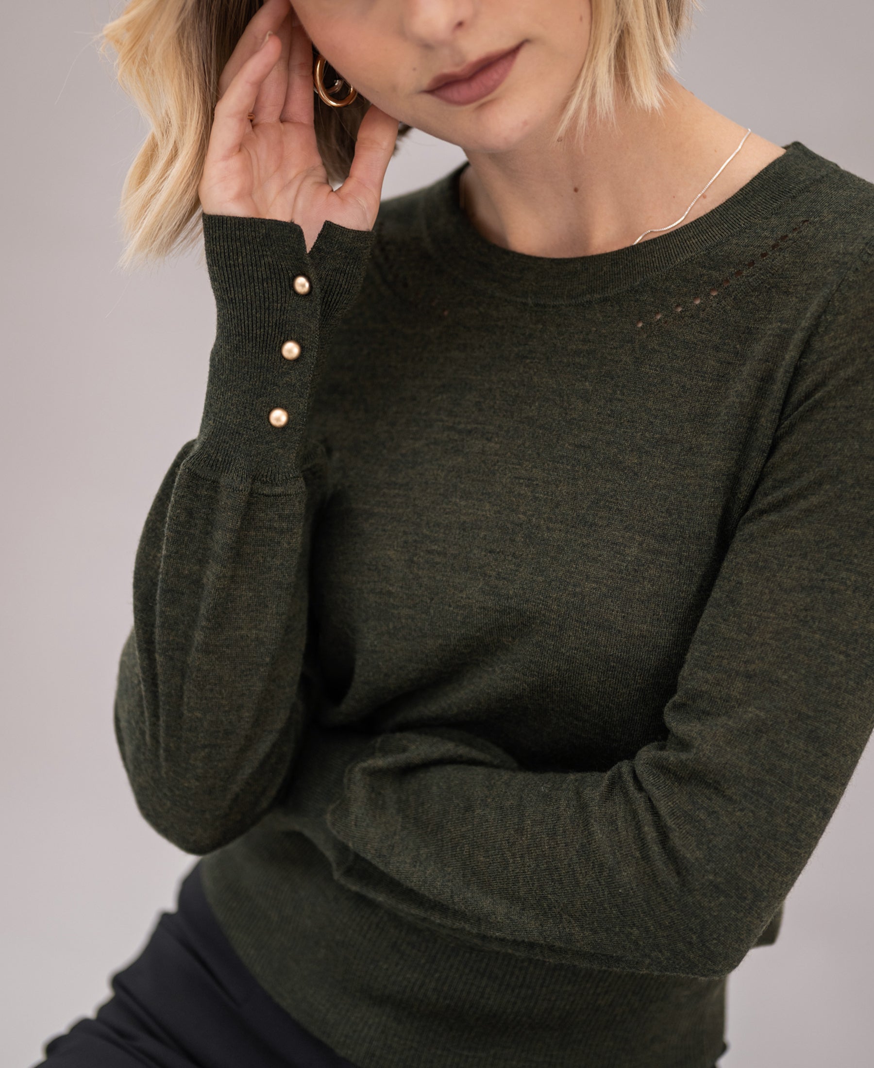 Dark green-gold merino wool sweater by PLEIN PUBLIQUE, LA MARIS style, partly visible on a woman.