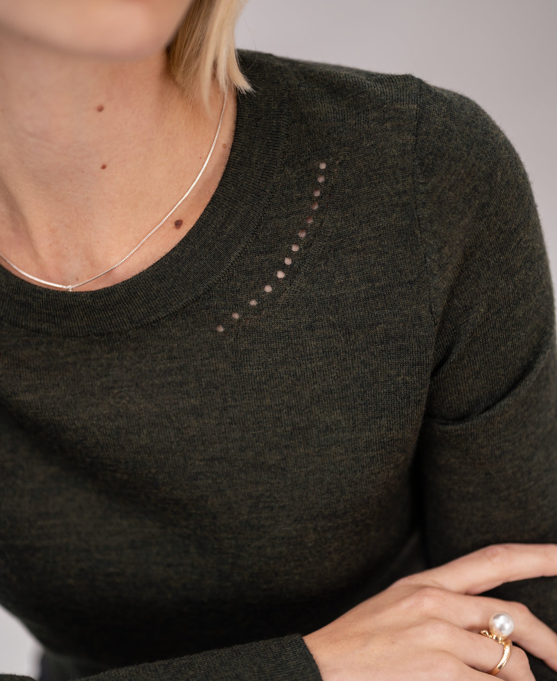 Dark green and gold merino wool sweater with small holes near the collar.
