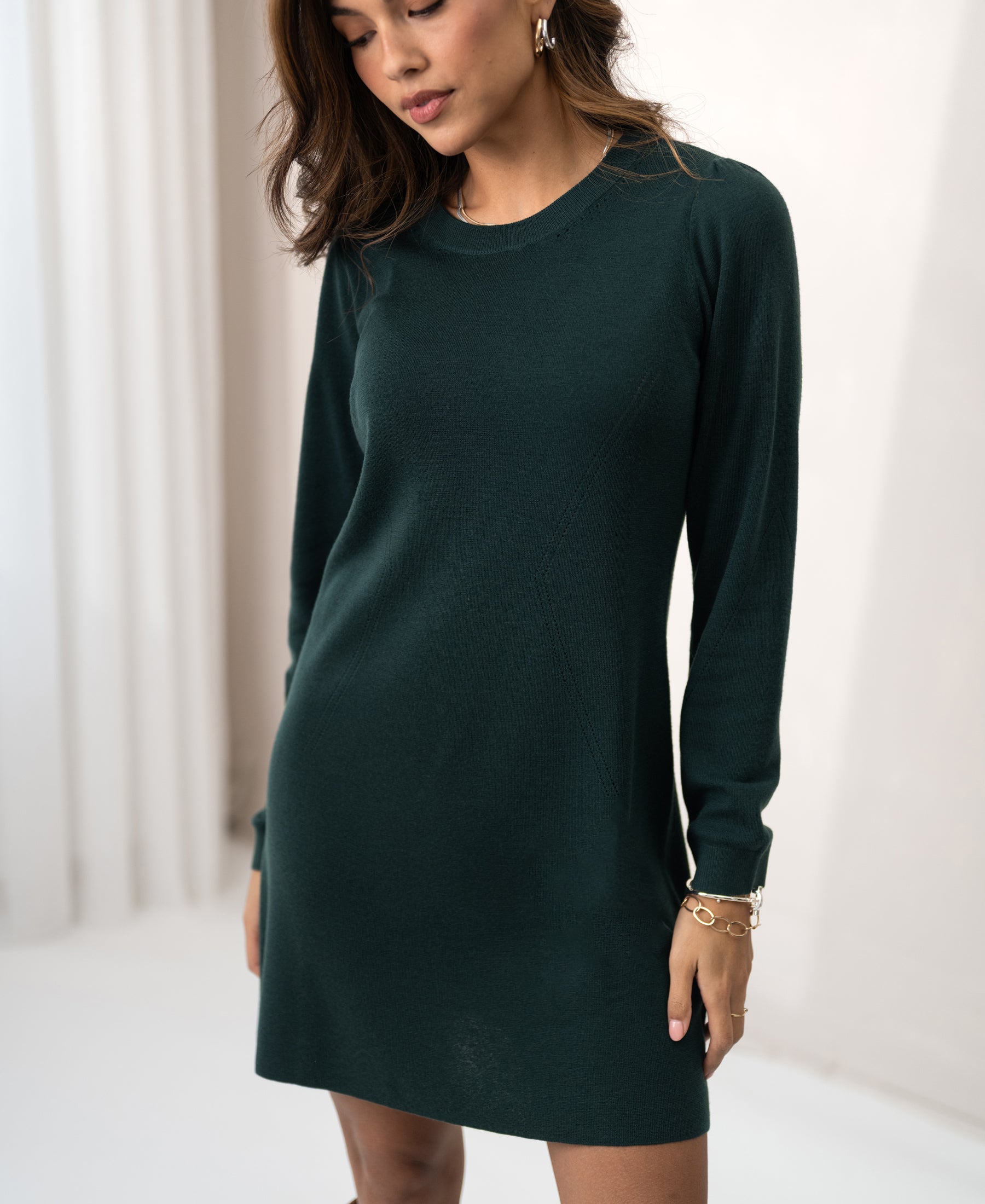 Woman modeling PLEIN PUBLIQUE merino wool dress in dark green indoors.